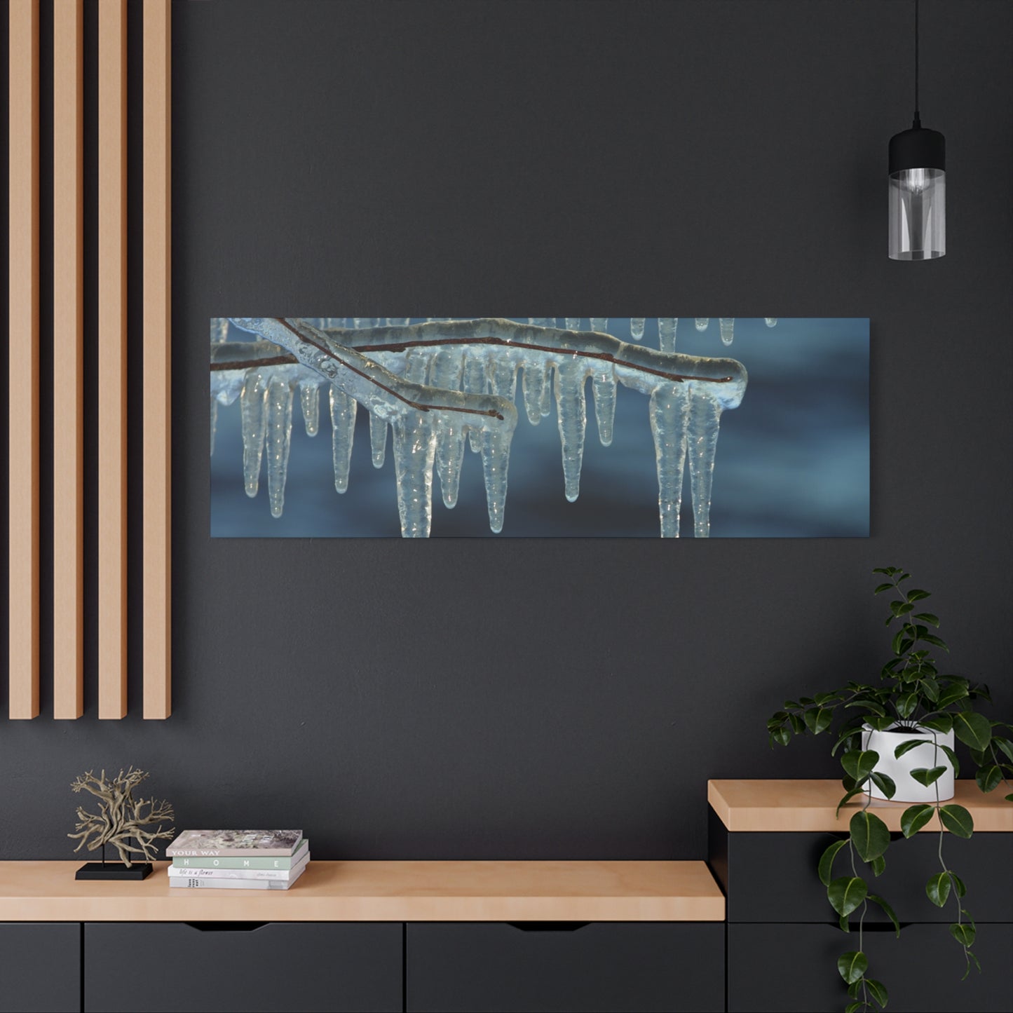 Panoramic photo of icicles hanging from a branch on a dark wall with wooden shelves below.