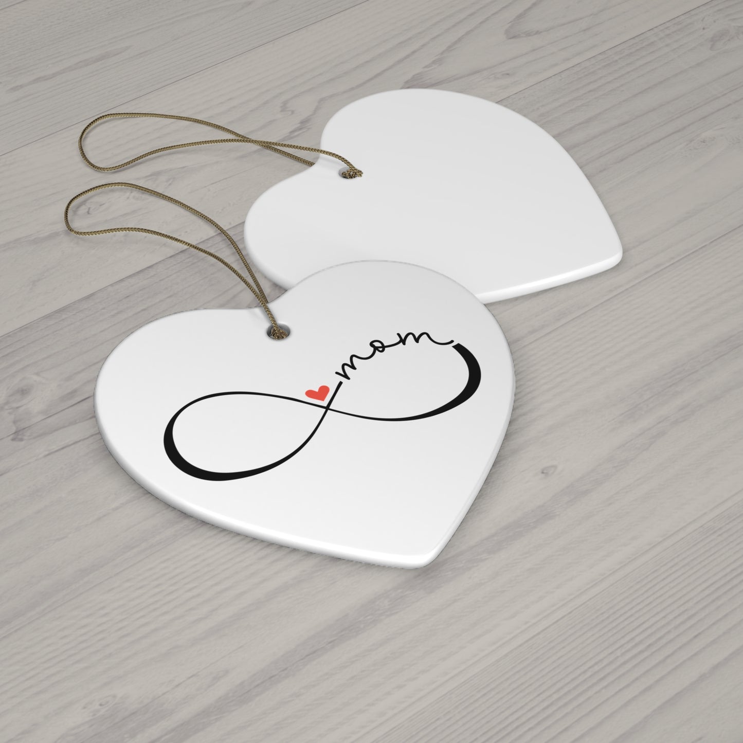 Heart-shaped ceramic tag with 'mom' and infinity symbol on a wooden surface