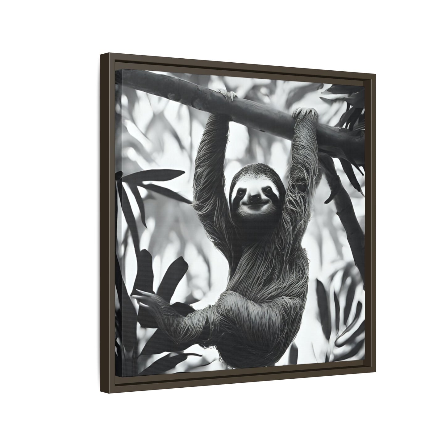 Framed black and white photo of a sloth hanging from a branch with leaves.