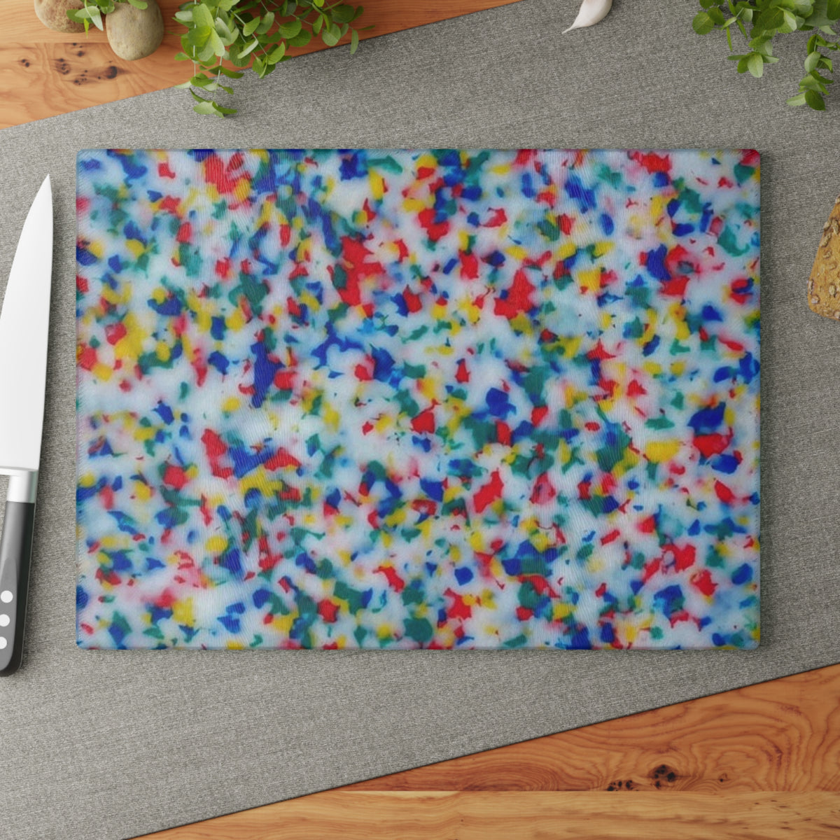Colorful speckled cutting board on a wooden surface with a knife.