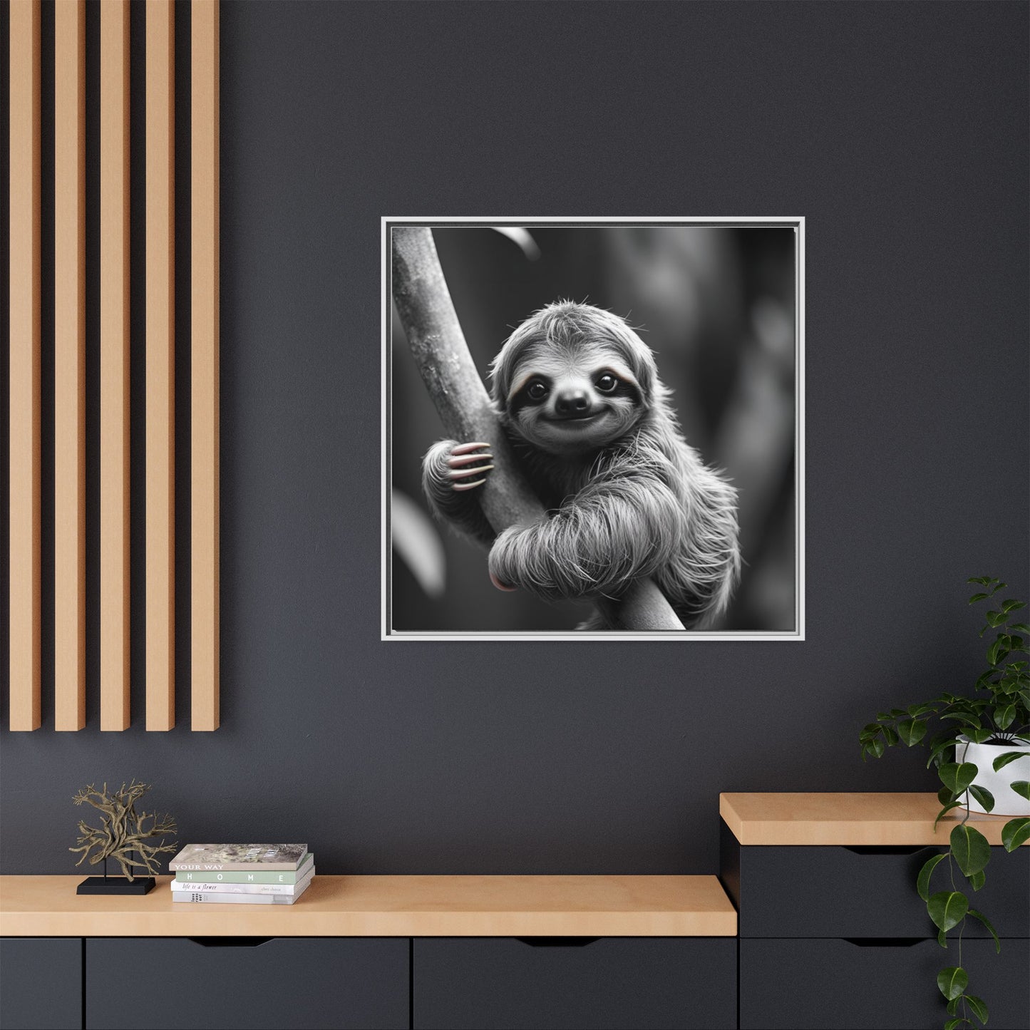Framed black and white sloth print on a dark wall with wooden shelves below.