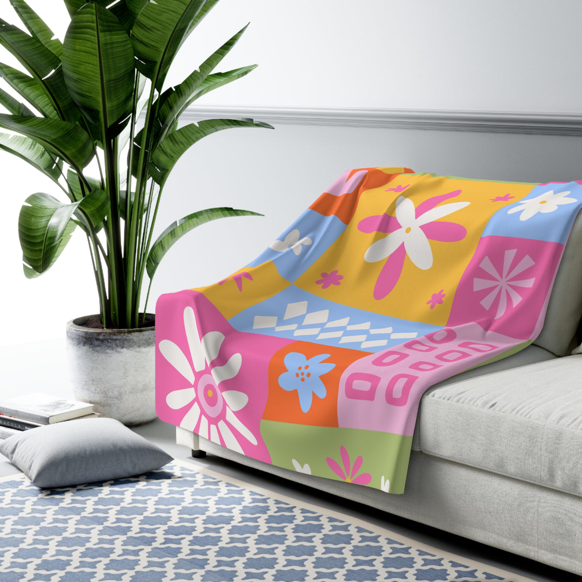 Colorful floral-patterned blanket on a gray sofa with a plant and rug in the background