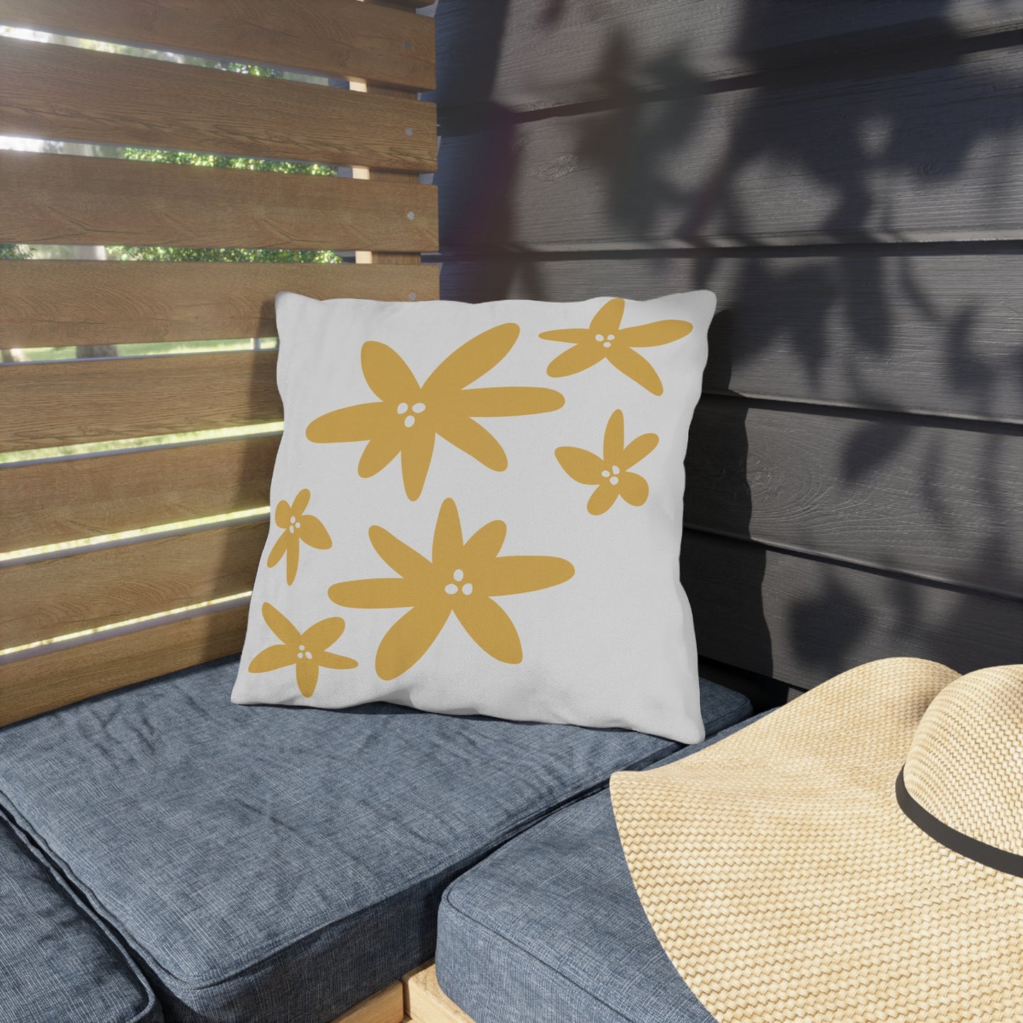 White pillow with yellow floral patterns on a gray outdoor cushion.