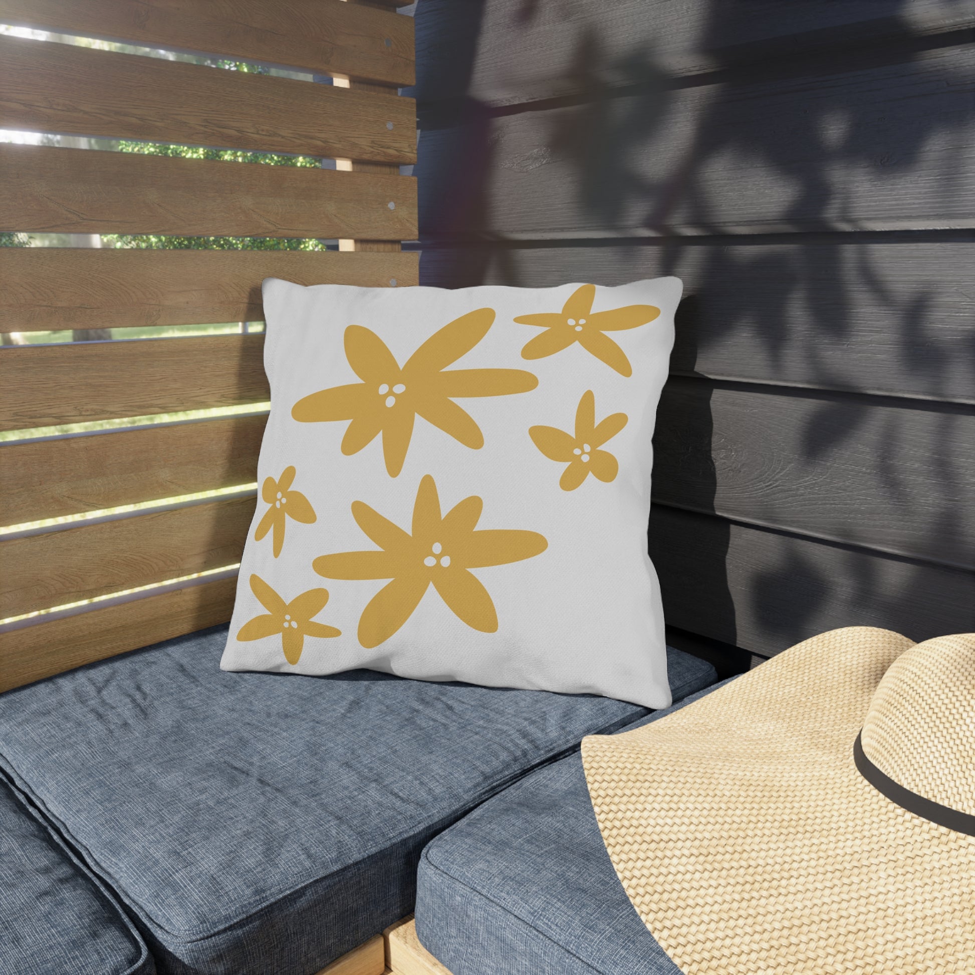 White pillow with yellow floral patterns on a gray outdoor cushion.