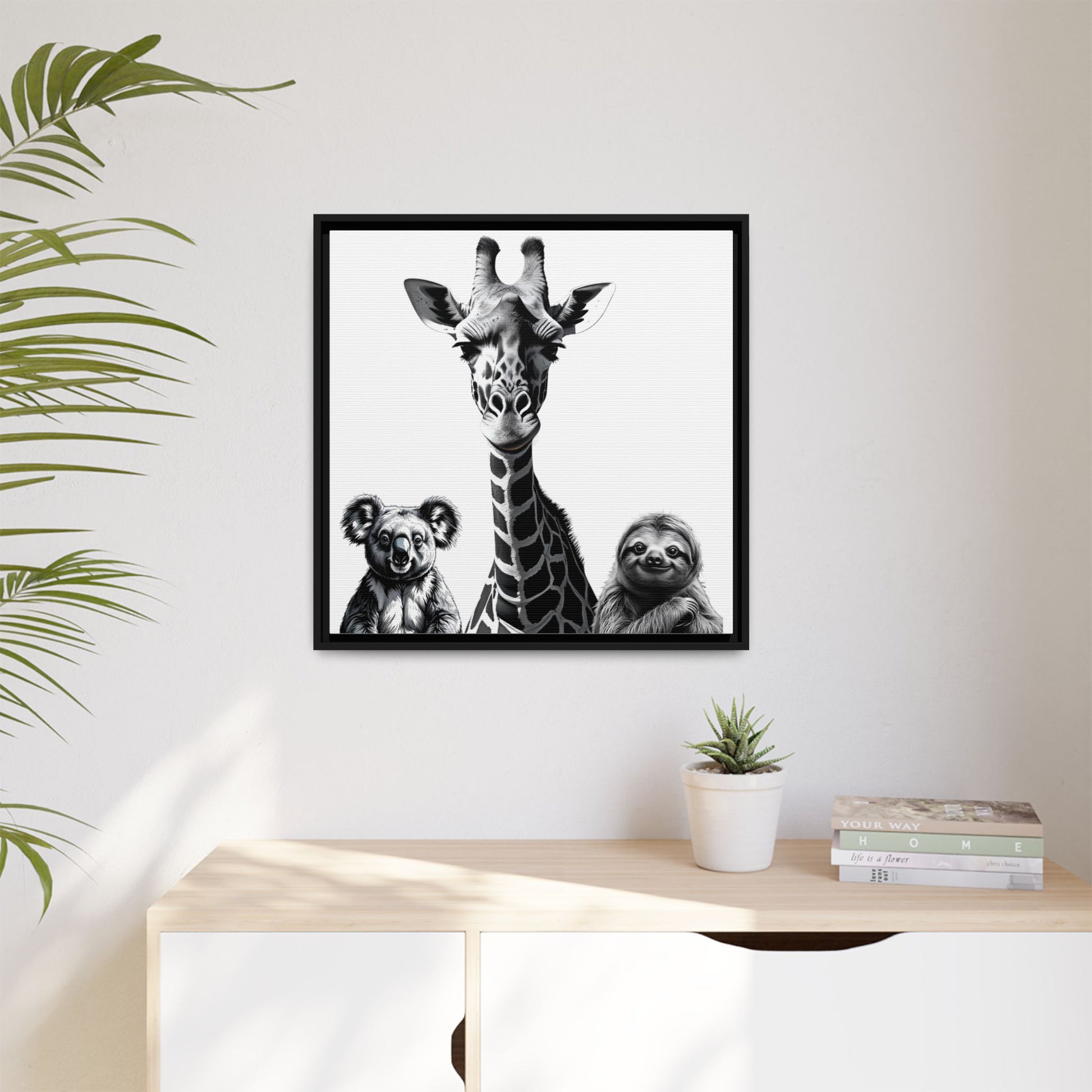 Framed artwork with a giraffe, koala, and sloth on a wall above a desk.