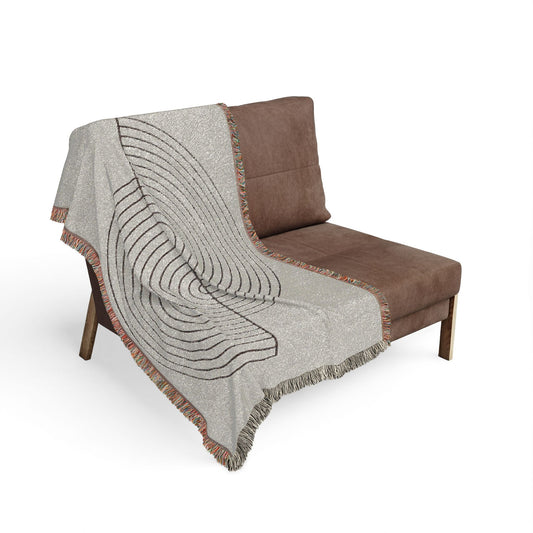 Gray textured throw blanket draped over a brown chair on a white background