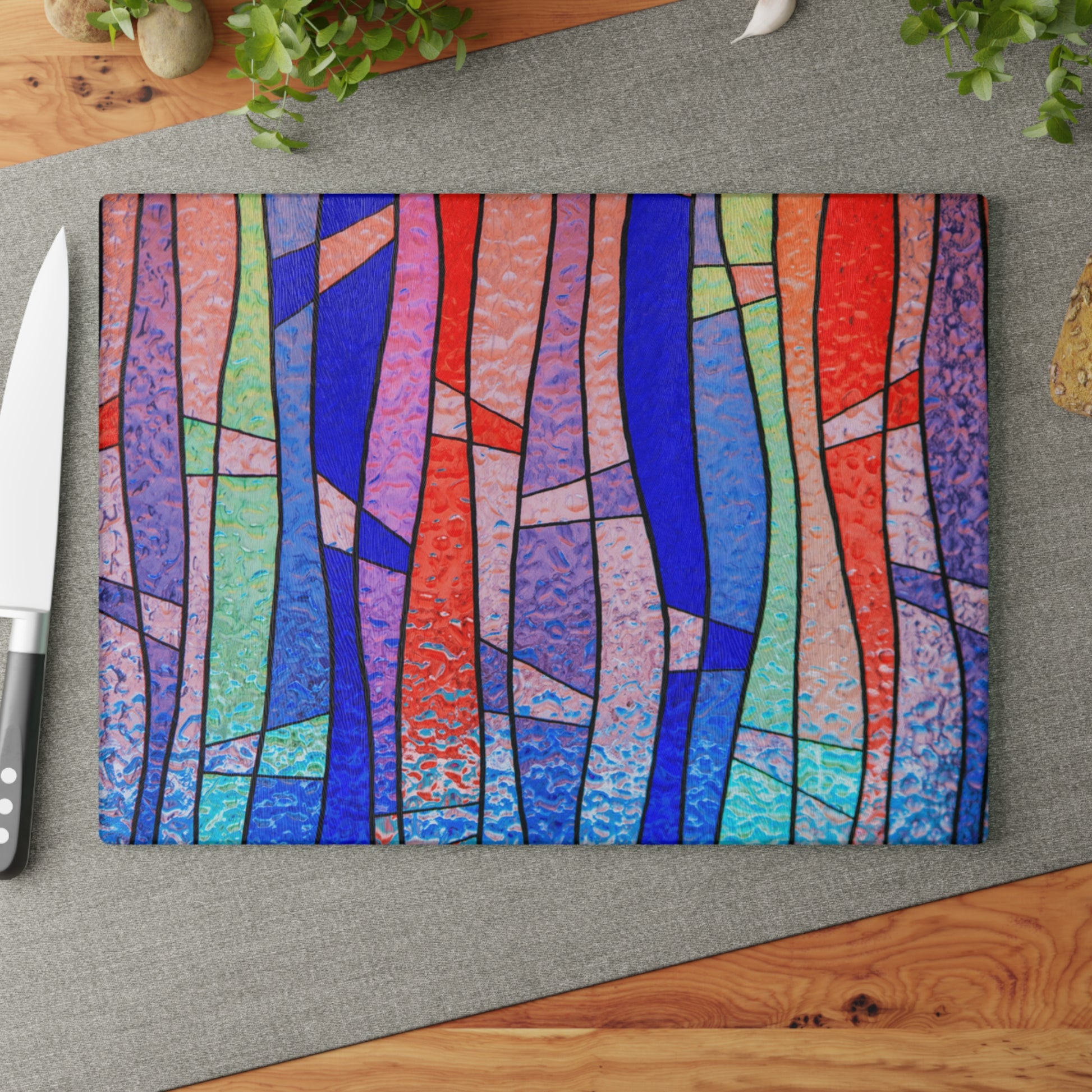 Colorful abstract patterned cutting board on a gray surface with a knife.