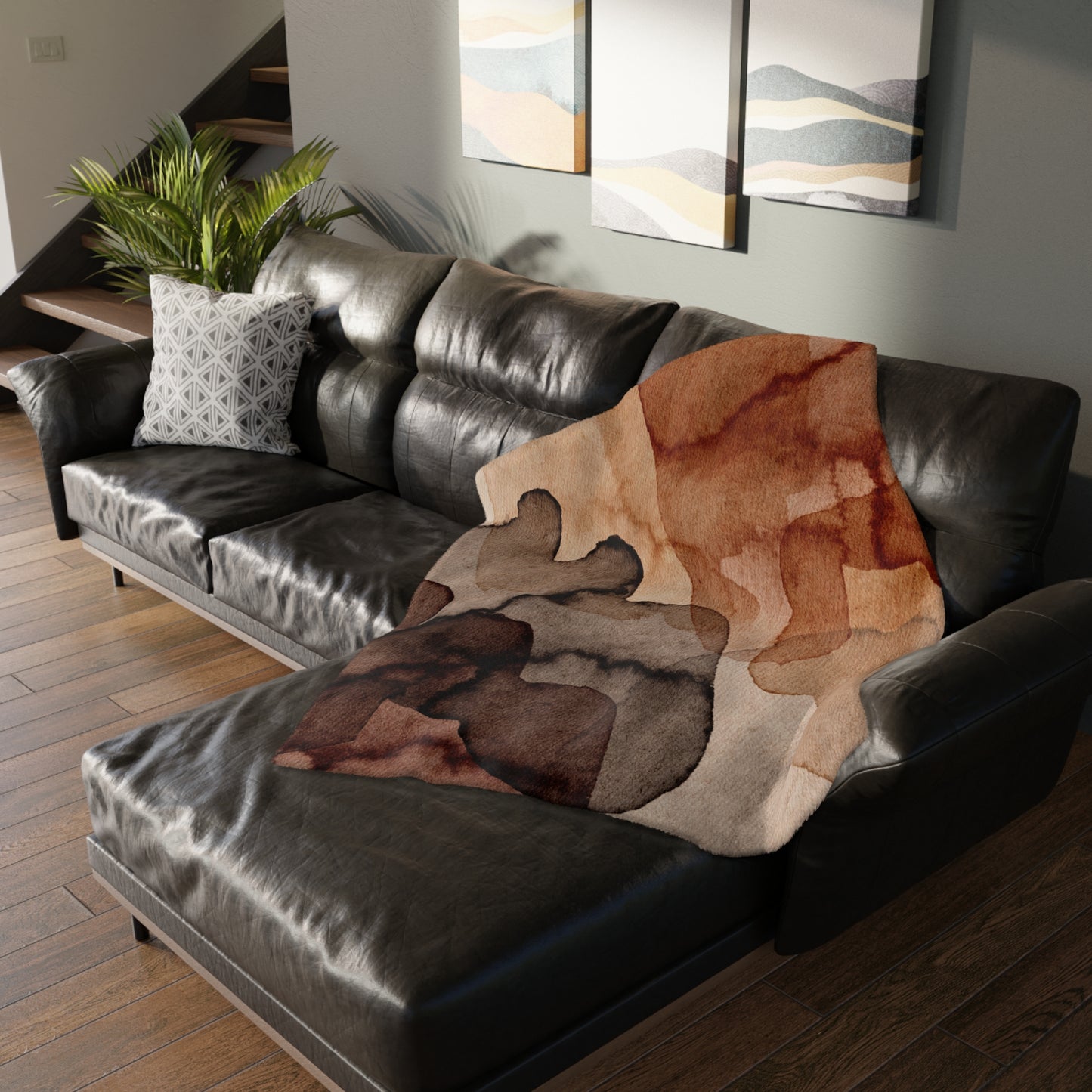 Brown patterned blanket draped over a black leather sofa in a living room.