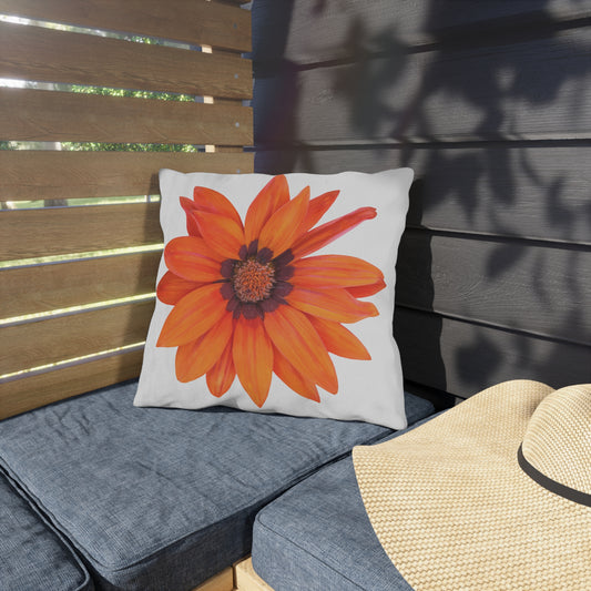 Decorative pillow with a large orange flower on a gray cushioned bench.
