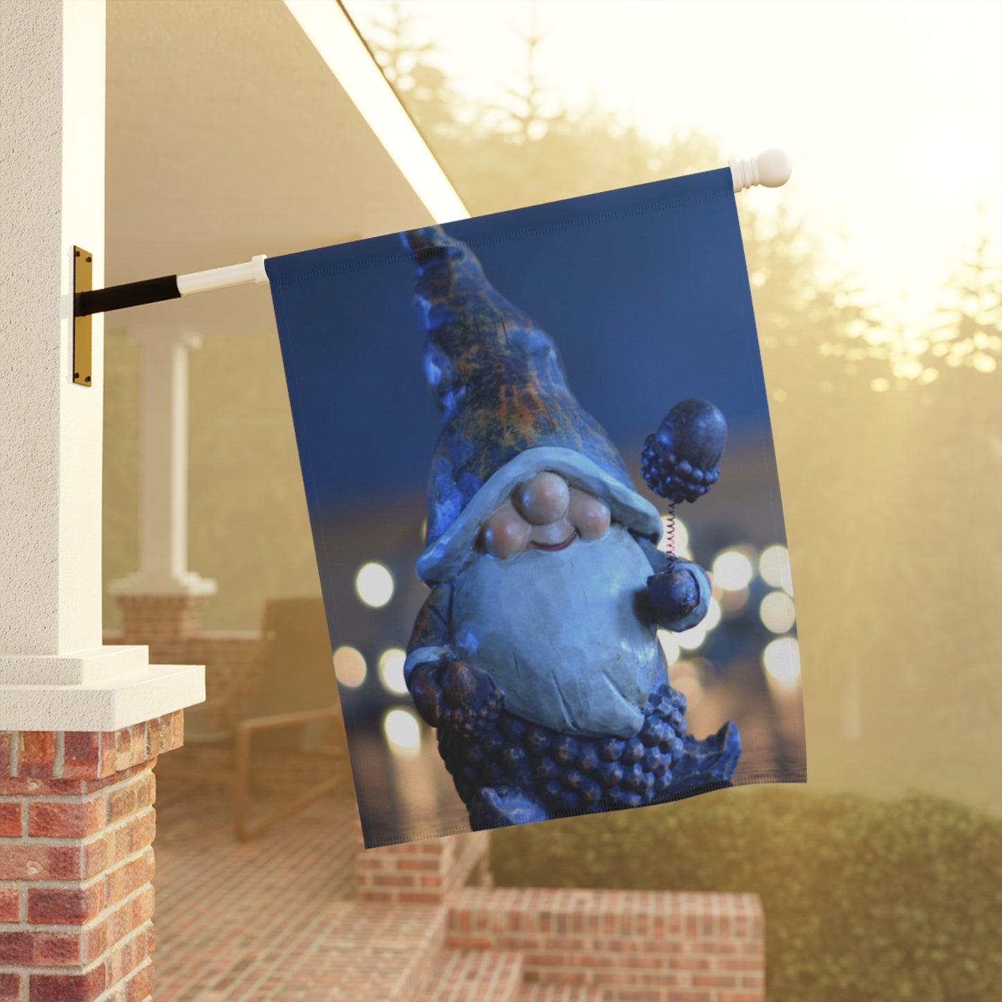 Decorative flag with a blue gnome design on a porch with lights in the background