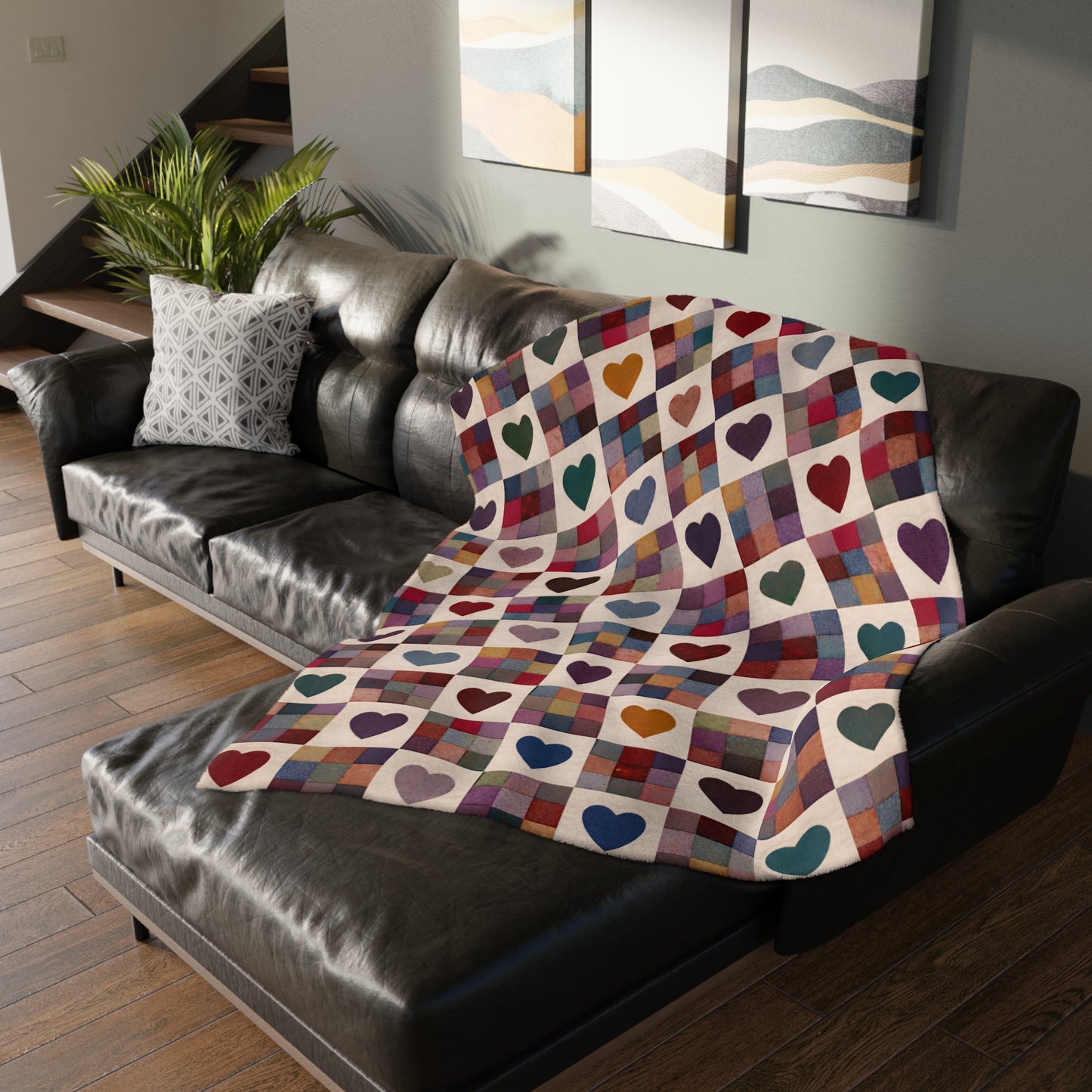 Colorful heart-patterned blanket draped over a black leather sofa in a living room.