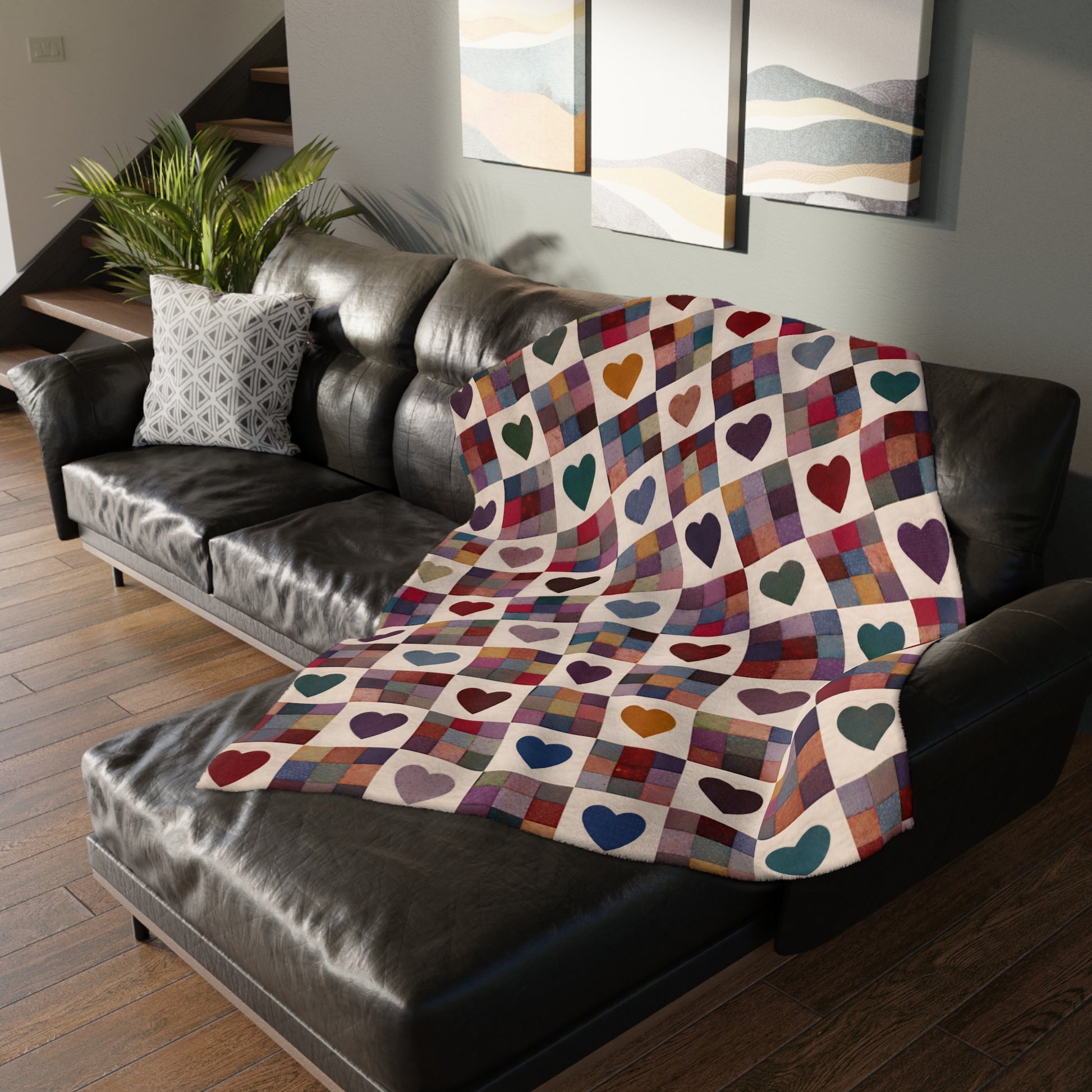 Colorful heart-patterned blanket draped over a black leather sofa in a living room.