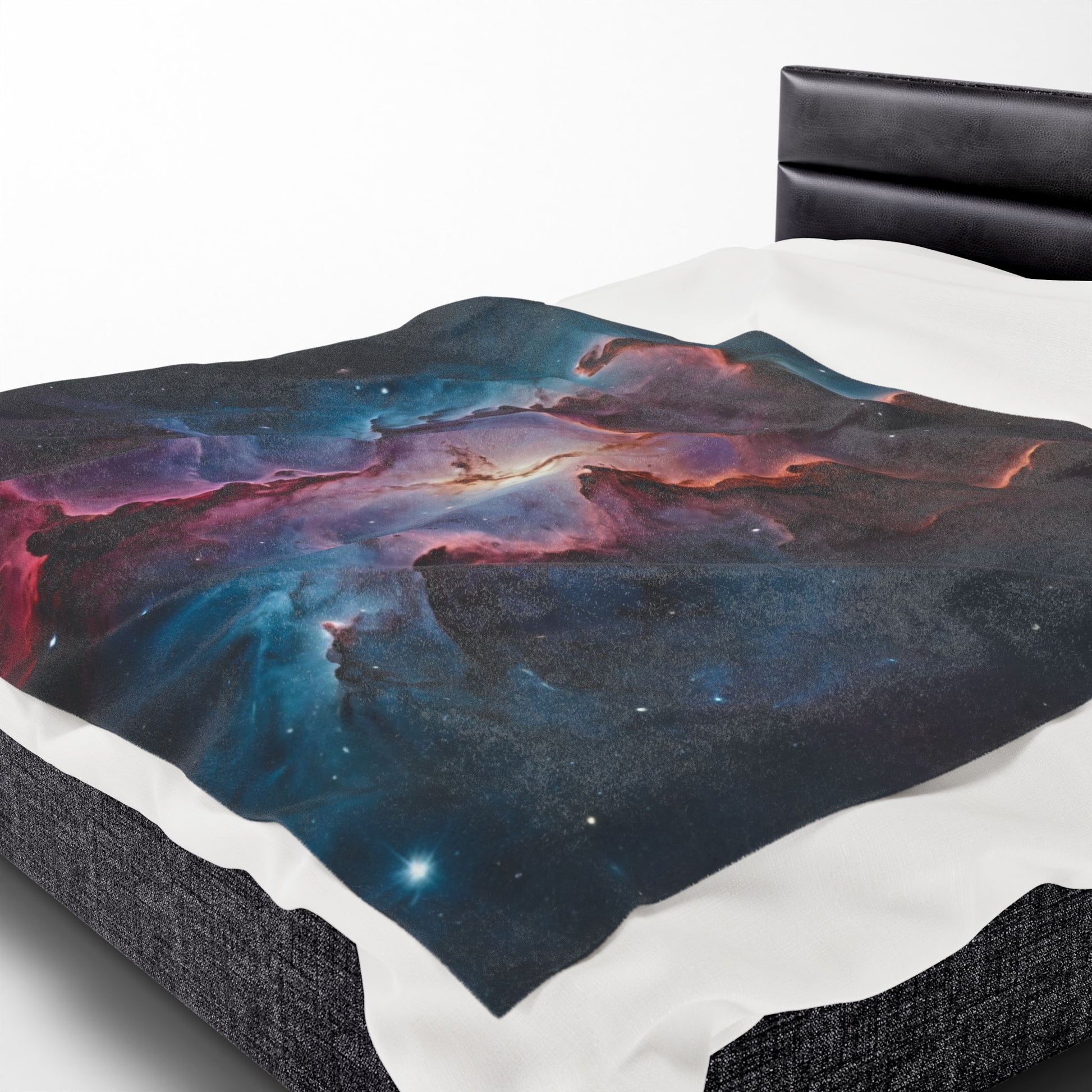 Neon galaxy blanket draped over a bed with a black headboard.