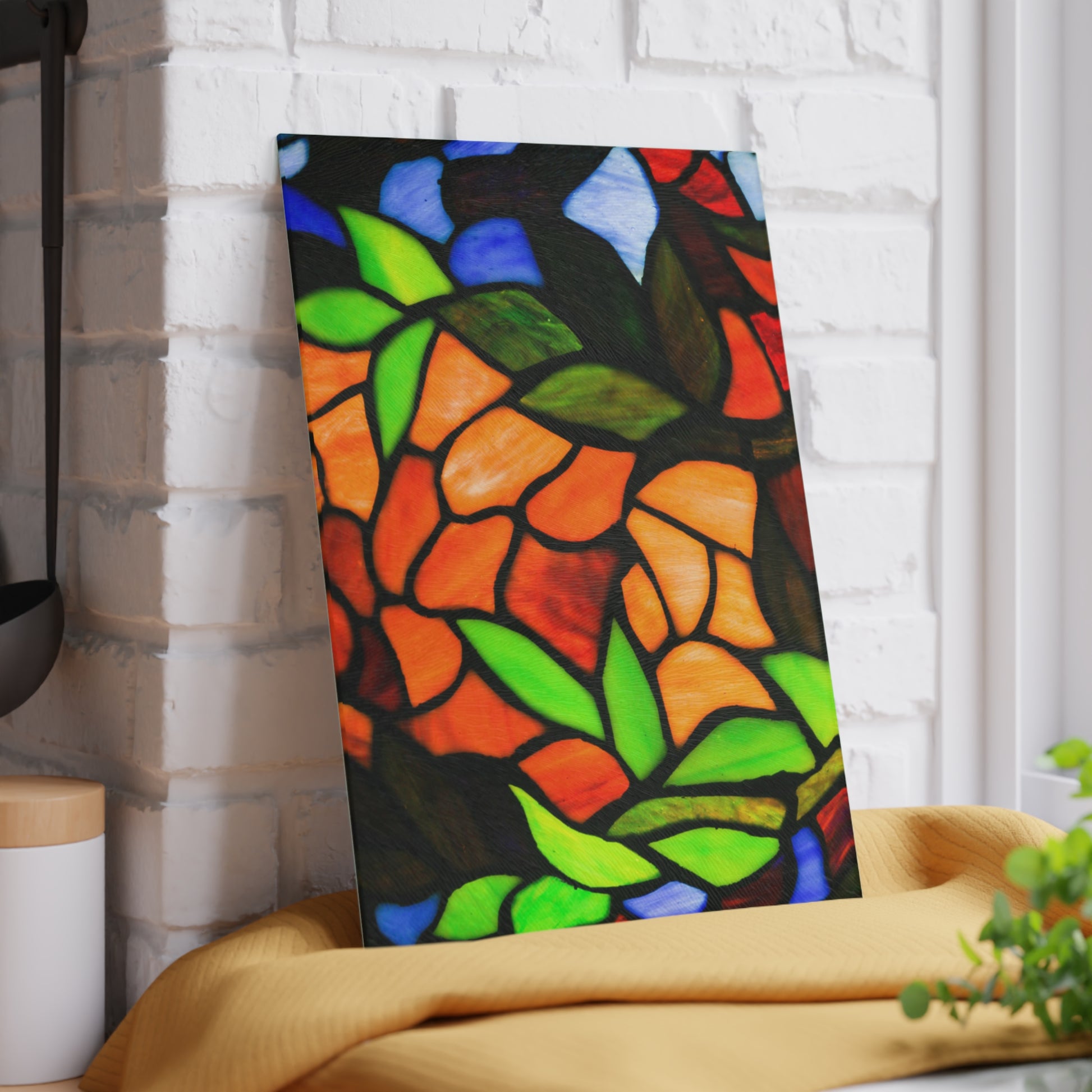 Colorful stained glass art piece leaning against a white brick wall.