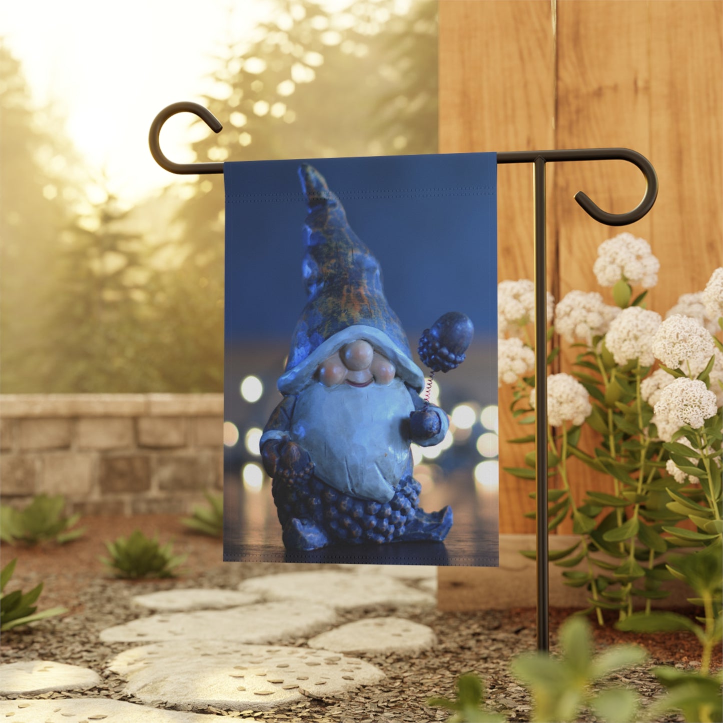 Garden flag with a blue gnome design on a stand outdoors.