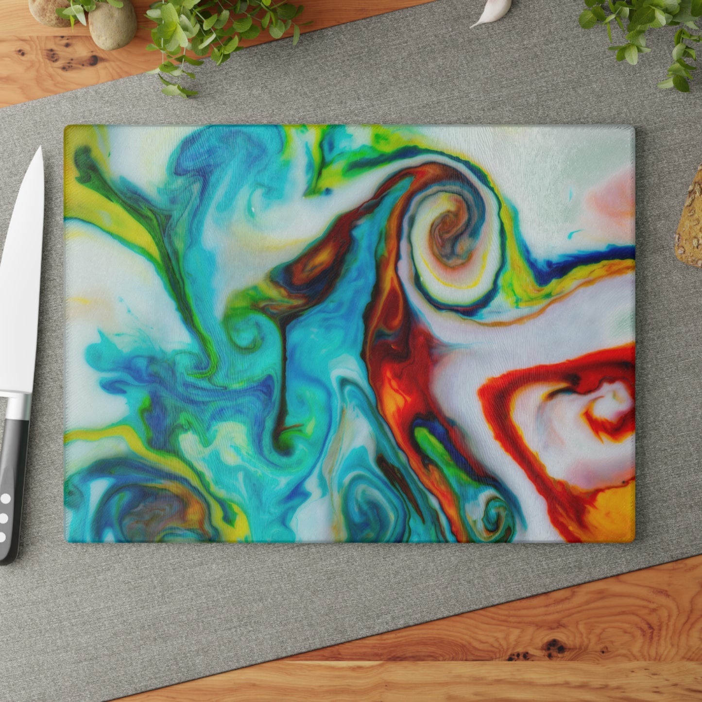Colorful abstract-patterned cutting board on a gray surface with a knife.