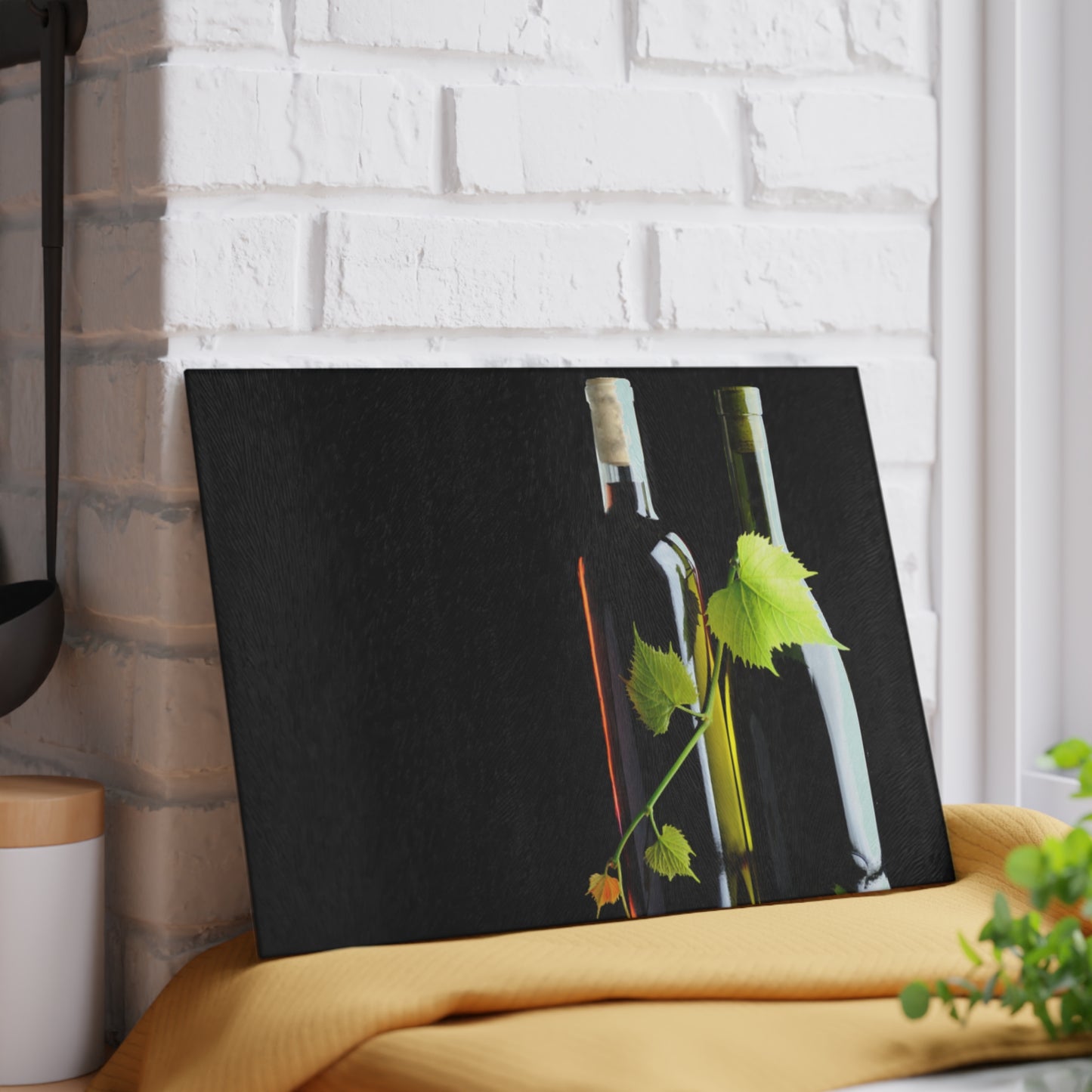Canvas print of wine bottles and leaves on a black background, leaning against a white brick wall.