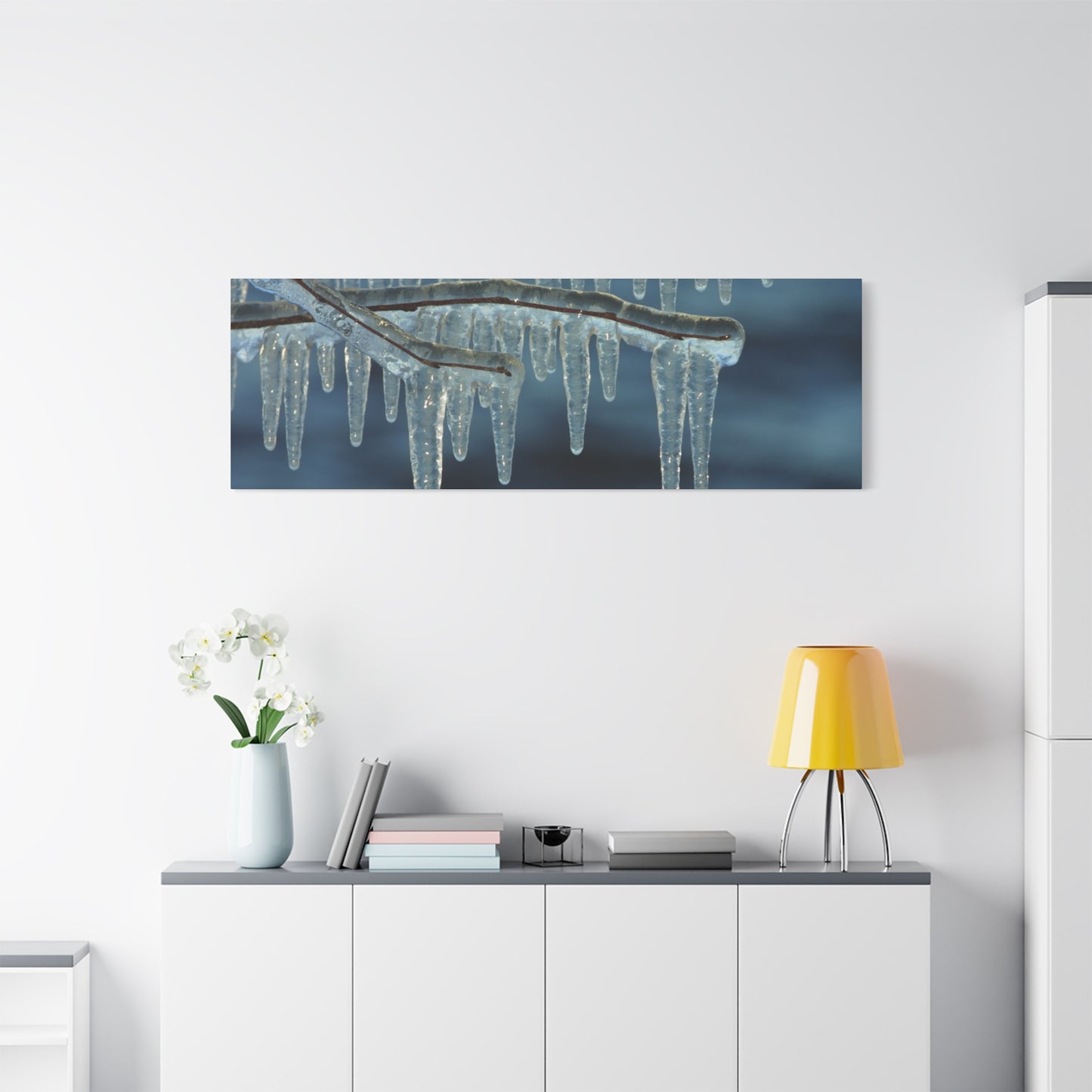 Framed artwork of icicles on a branch above a white cabinet with decorative items.