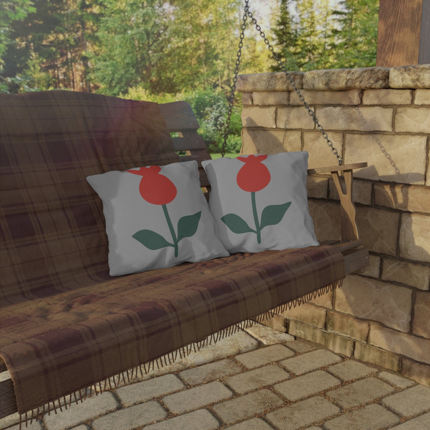 Wooden swing with plaid cover and floral-patterned cushions in a garden setting.
