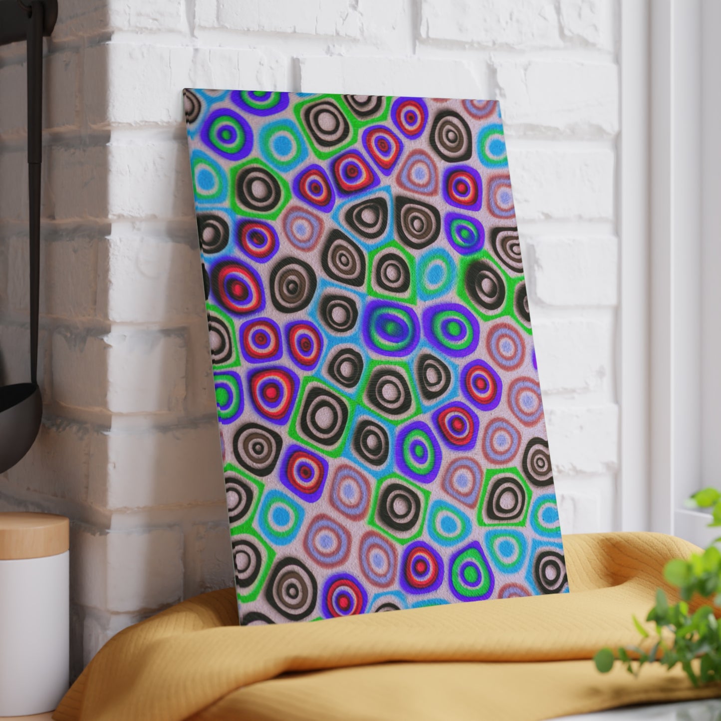 Colorful circular patterned towel hanging on a white brick wall.