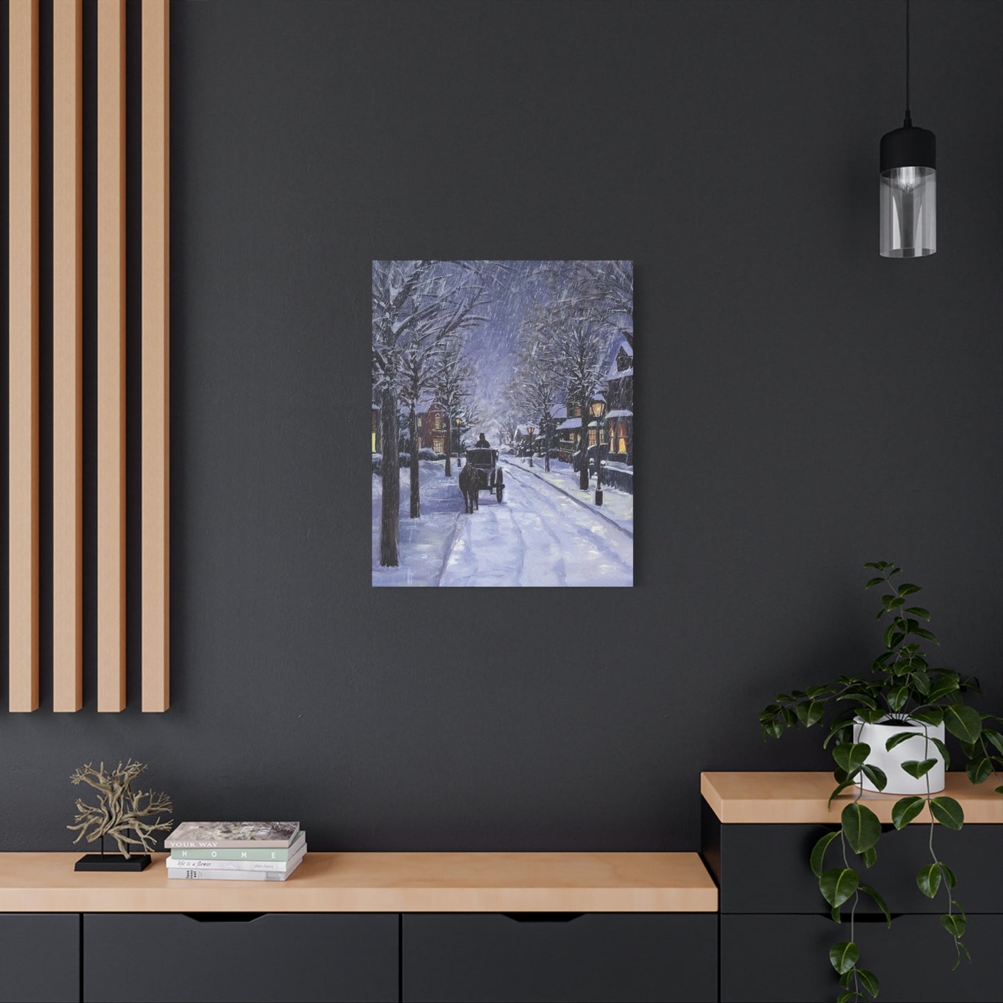 Framed artwork of a snowy street scene on a dark wall above a wooden console table.