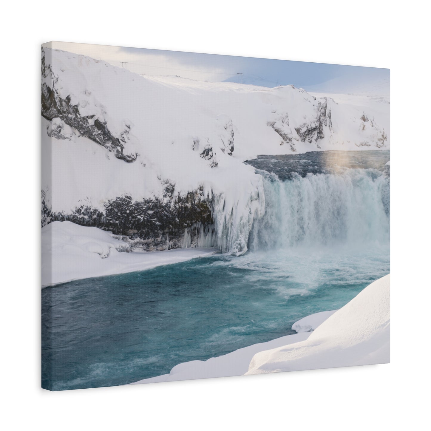 Canvas print of a snowy landscape with a waterfall and blue water.