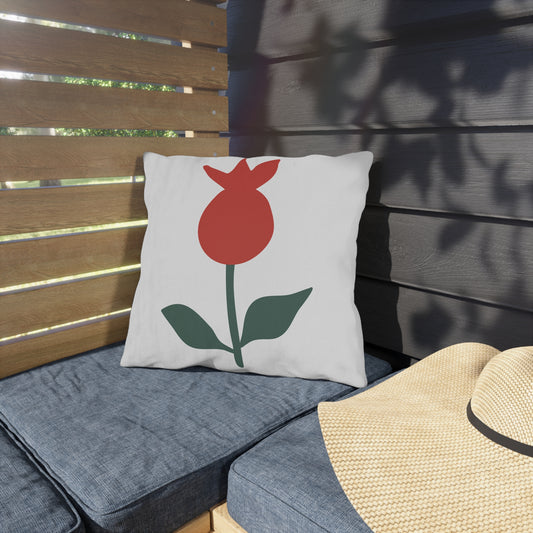 Pillow with a red flower design on a wooden bench