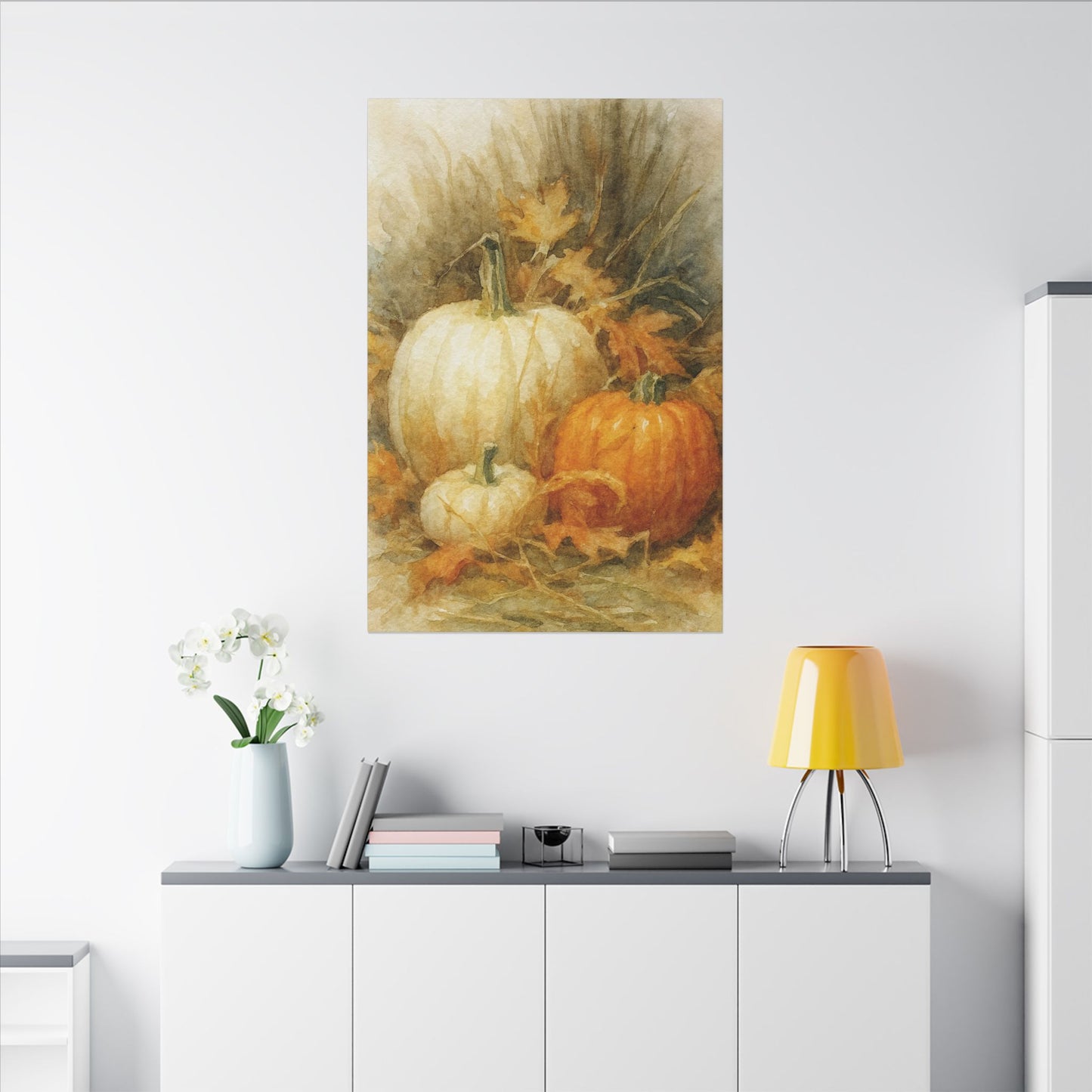 Framed artwork of pumpkins on a wall above a white cabinet with decor items.