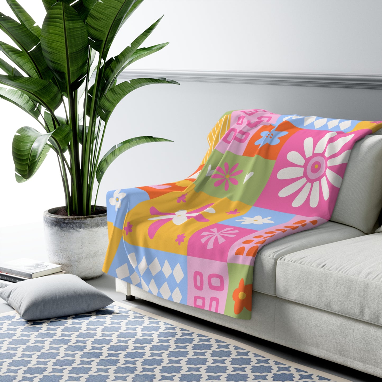 Colorful floral-patterned blanket on a gray sofa with a plant and rug in the background