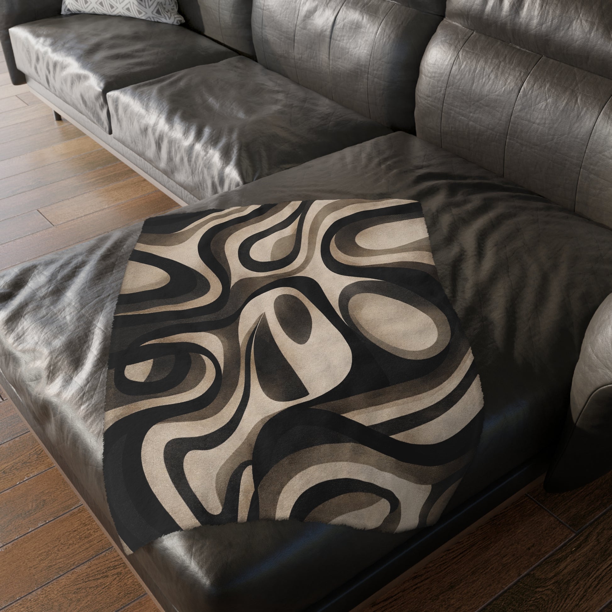Patterned pillow on a brown leather sofa with wooden floor.