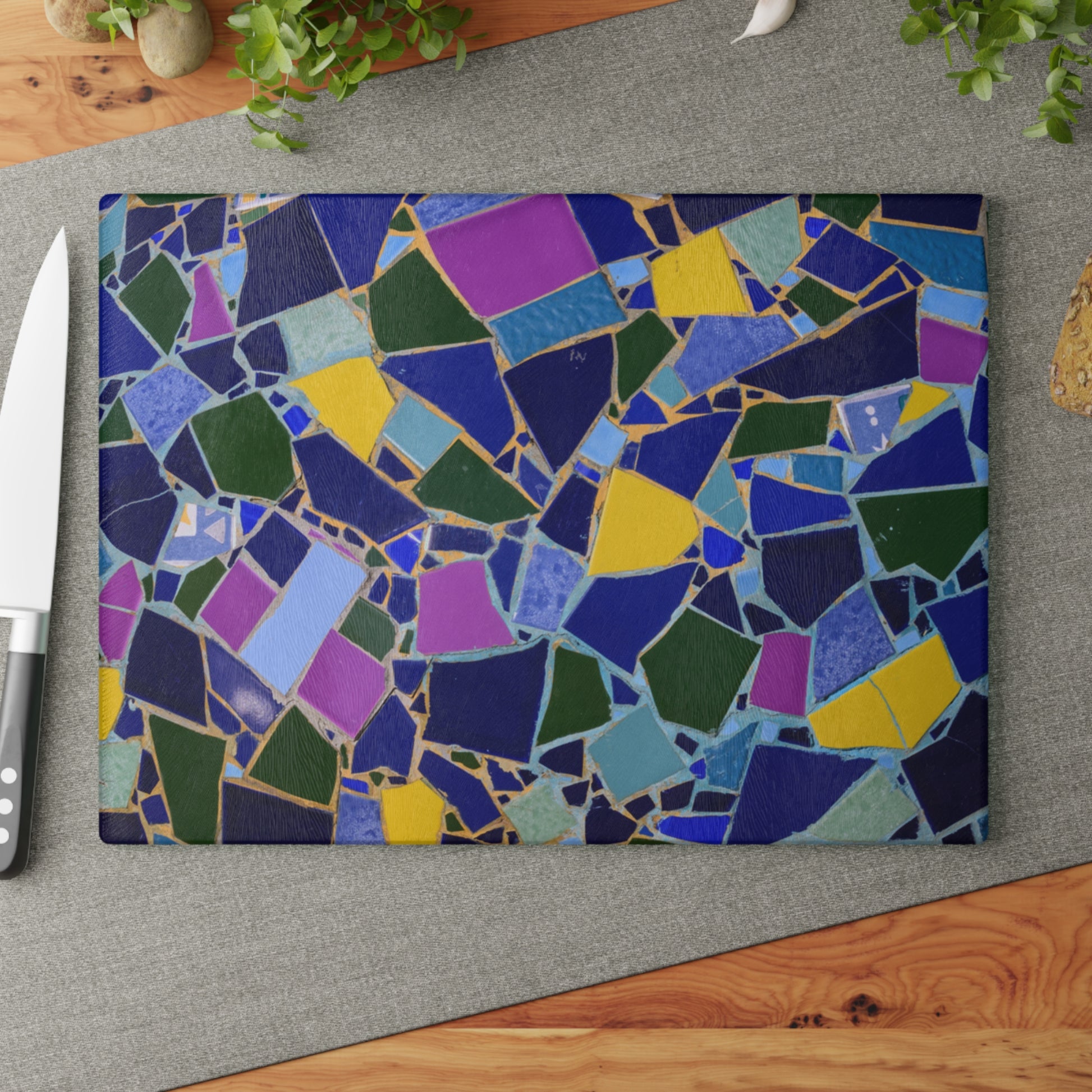 Colorful mosaic cutting board on a gray surface with a knife to the left.