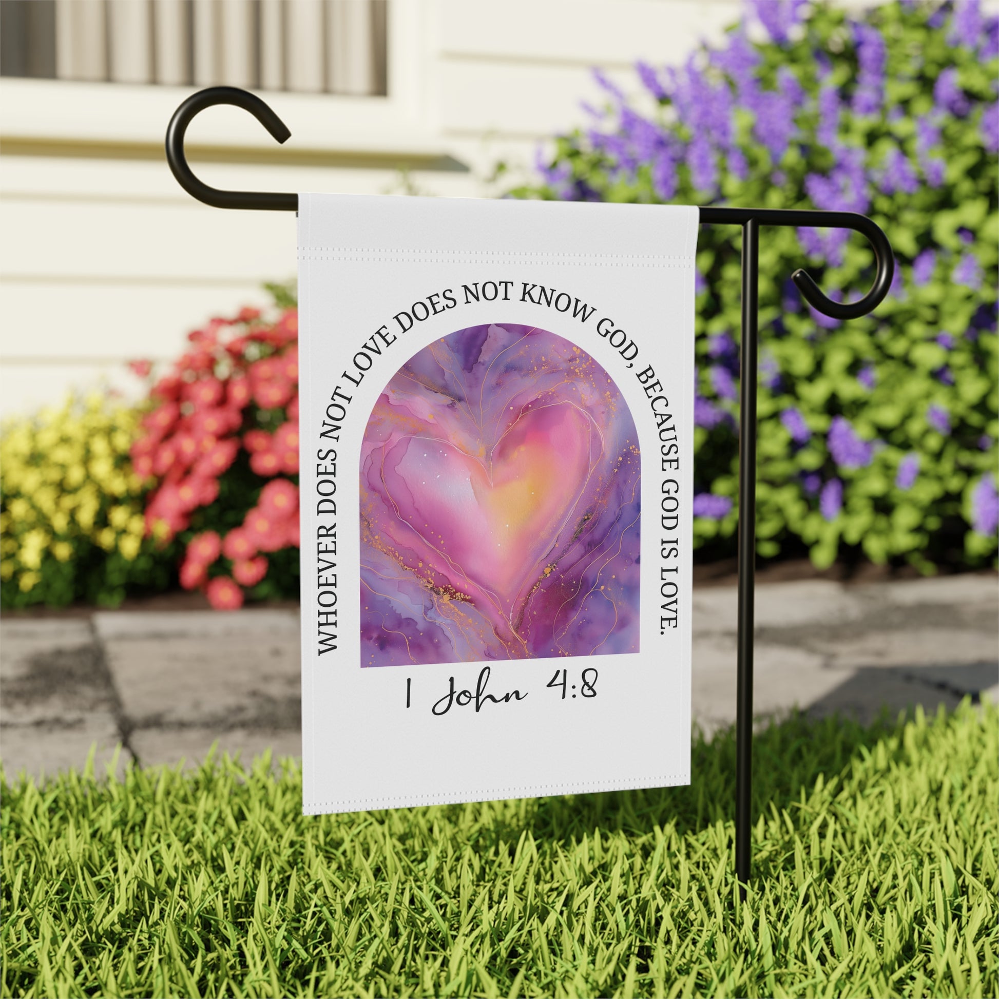Garden flag with heart design and text on a stand in front of flowers
