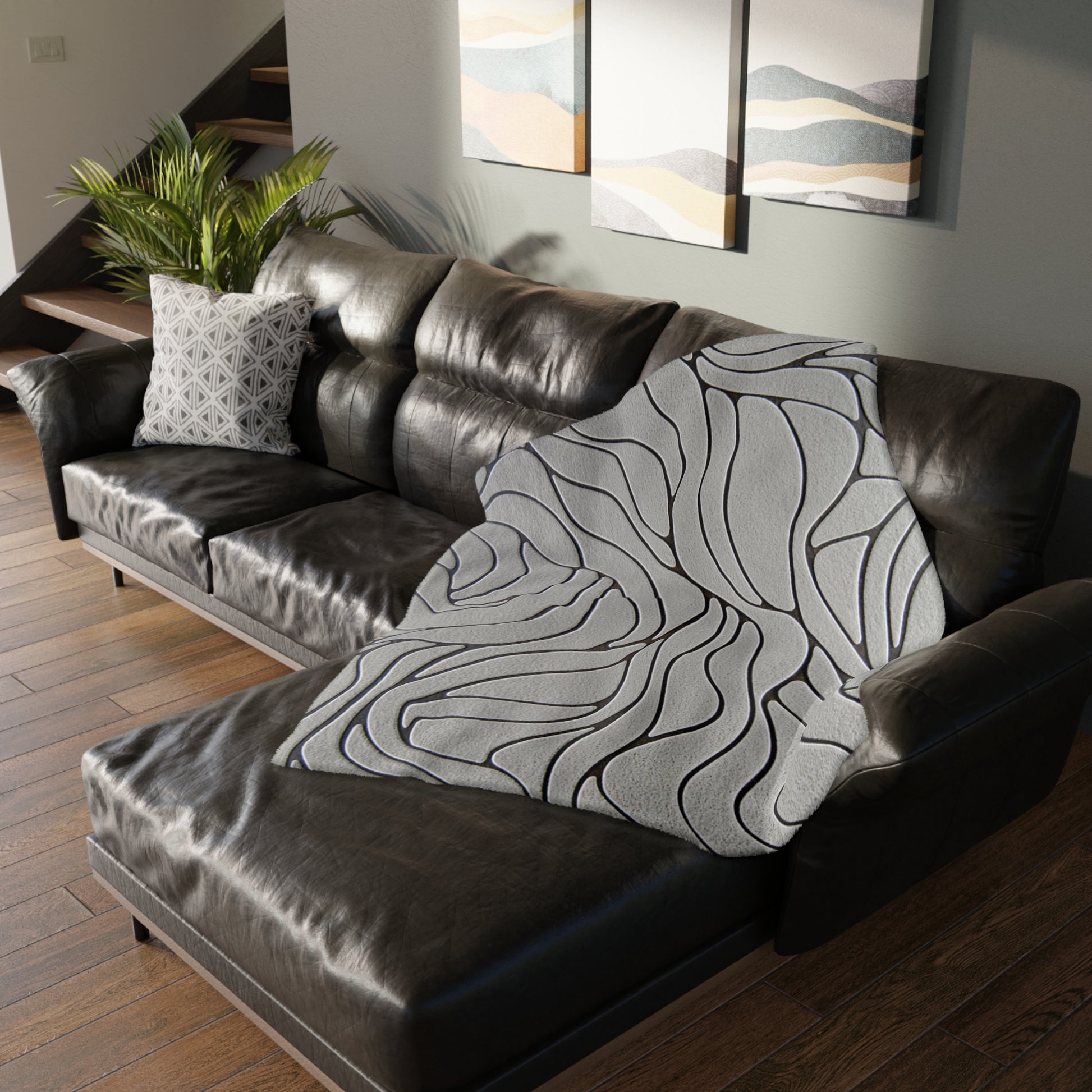 Brown leather sectional sofa with a patterned gray throw blanket in a living room setting.