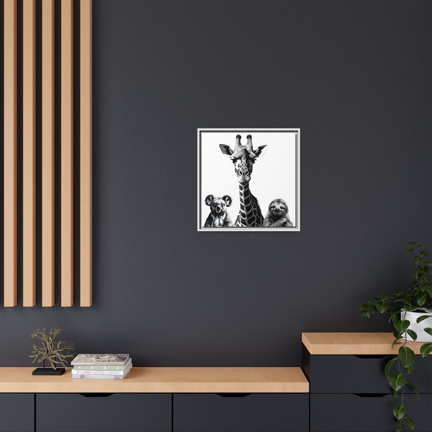 Framed artwork of a giraffe and sloths on a dark wall with wooden shelves below.