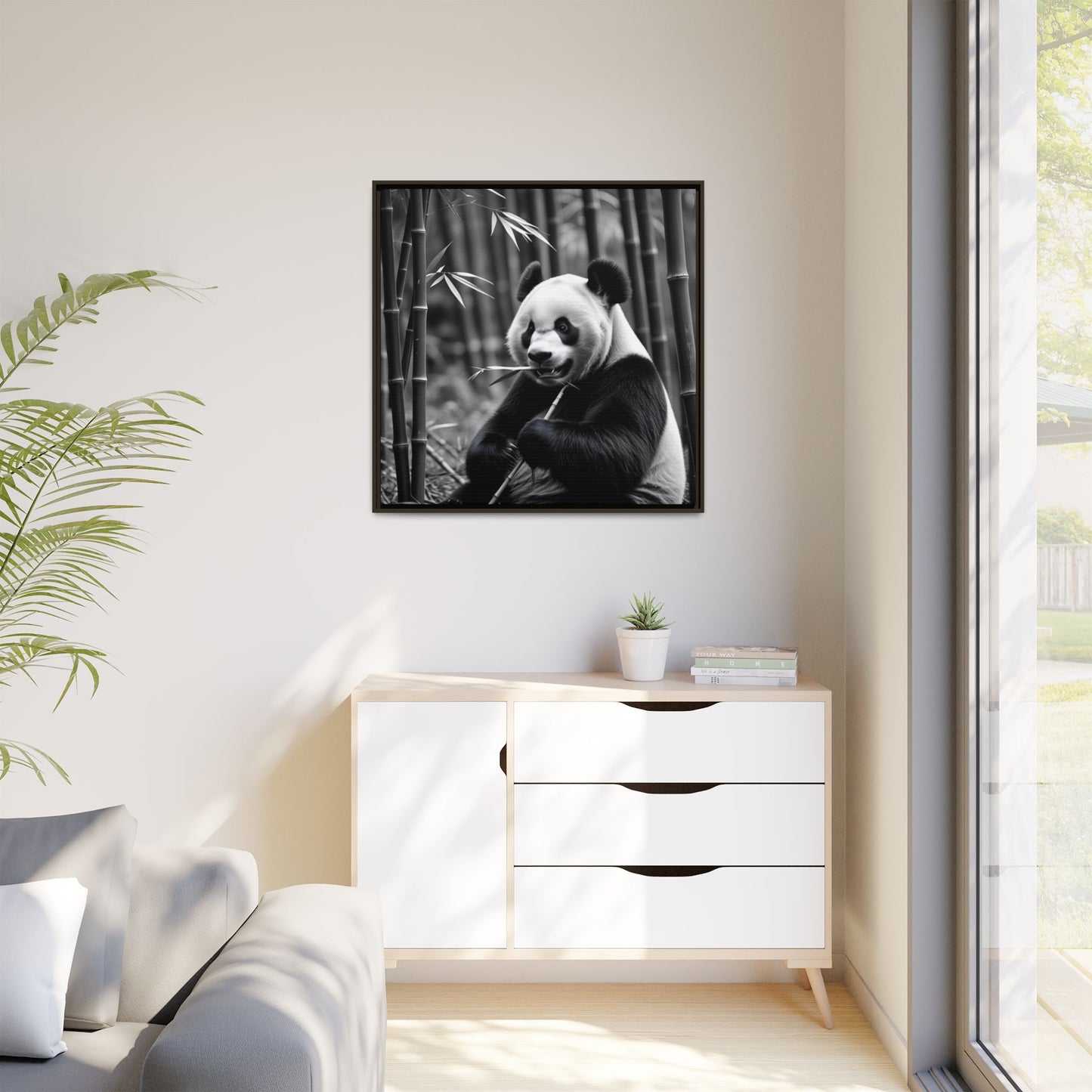 Framed black and white panda print on a wall above a white cabinet.