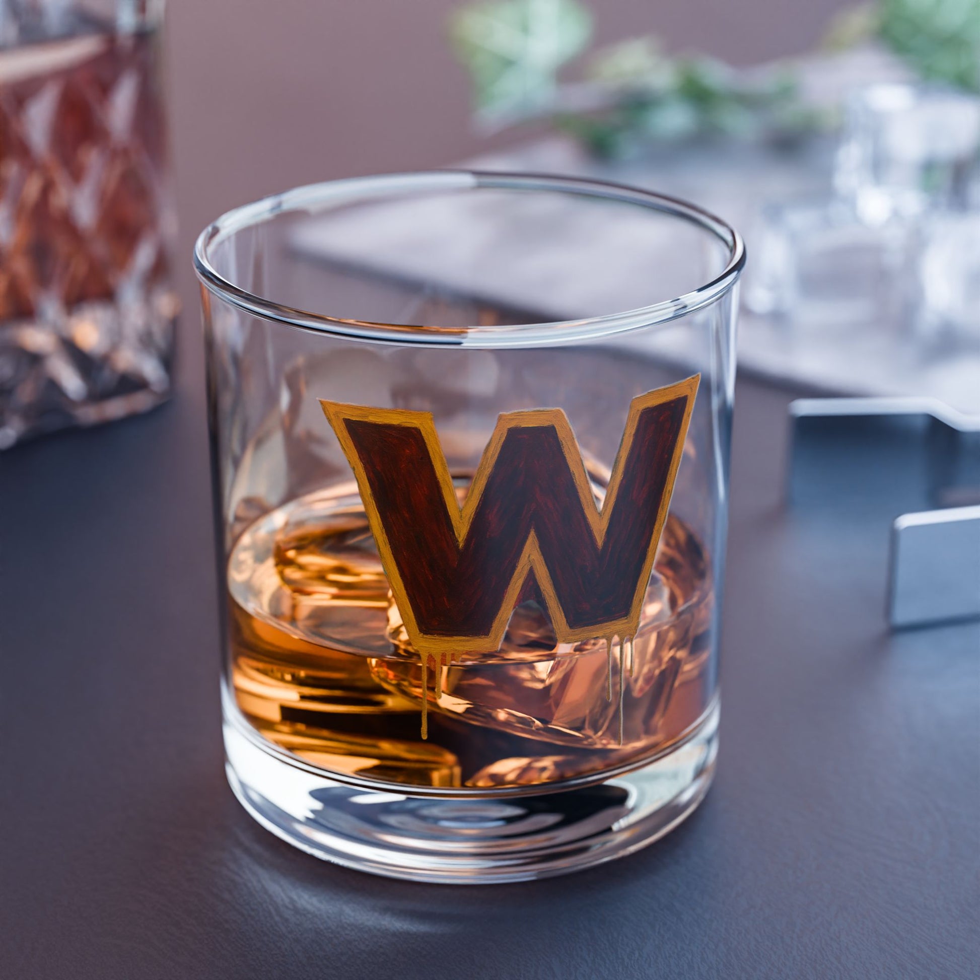 Glass with a 'W' logo filled with amber liquid on a dark surface.