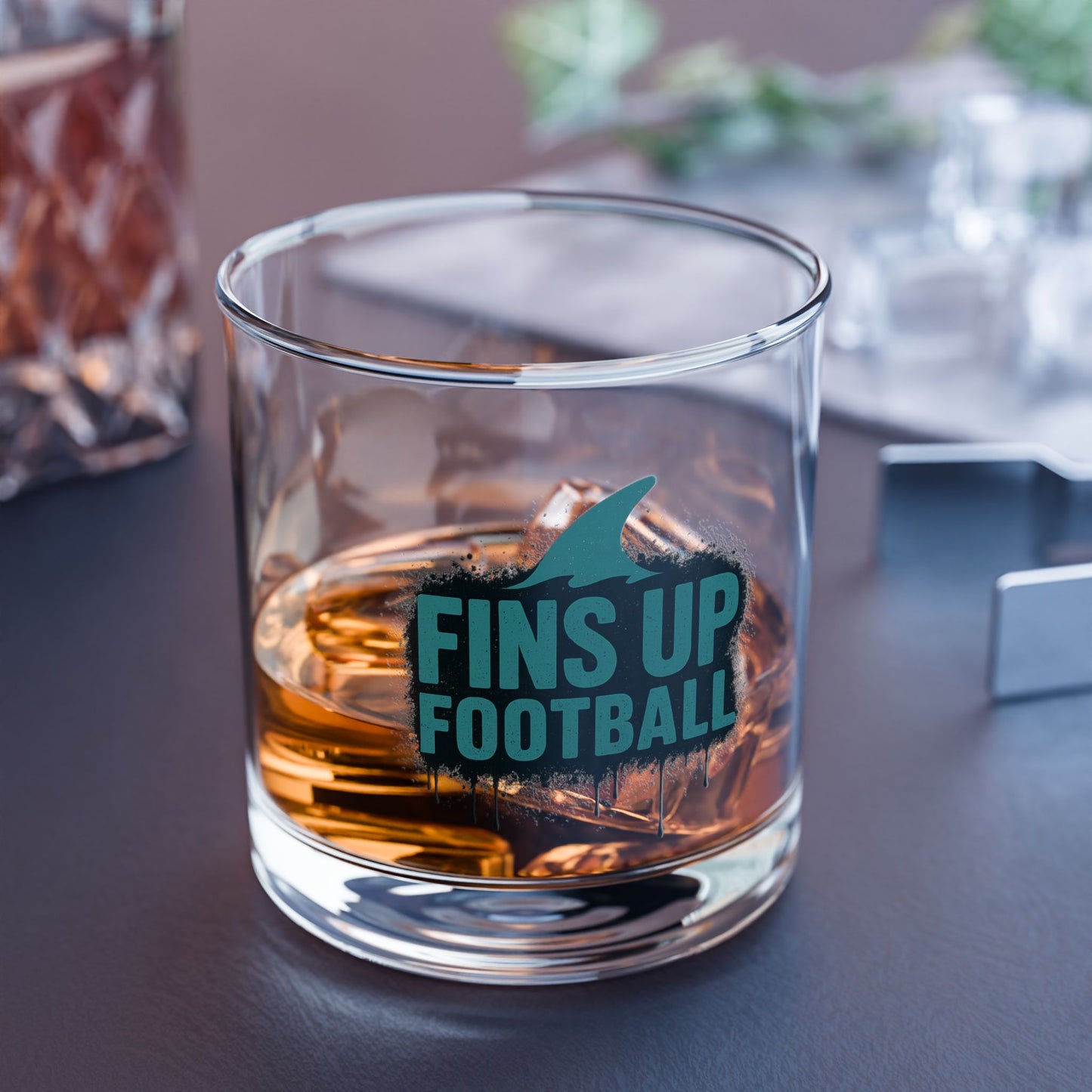 Glass with 'FINS UP FOOTBALL' text and醉酒液体 on a table.