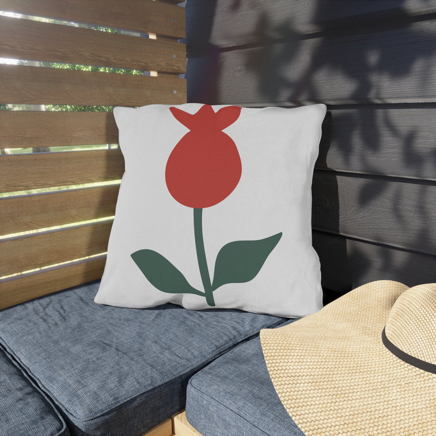 Decorative pillow with a red flower design on a wooden bench