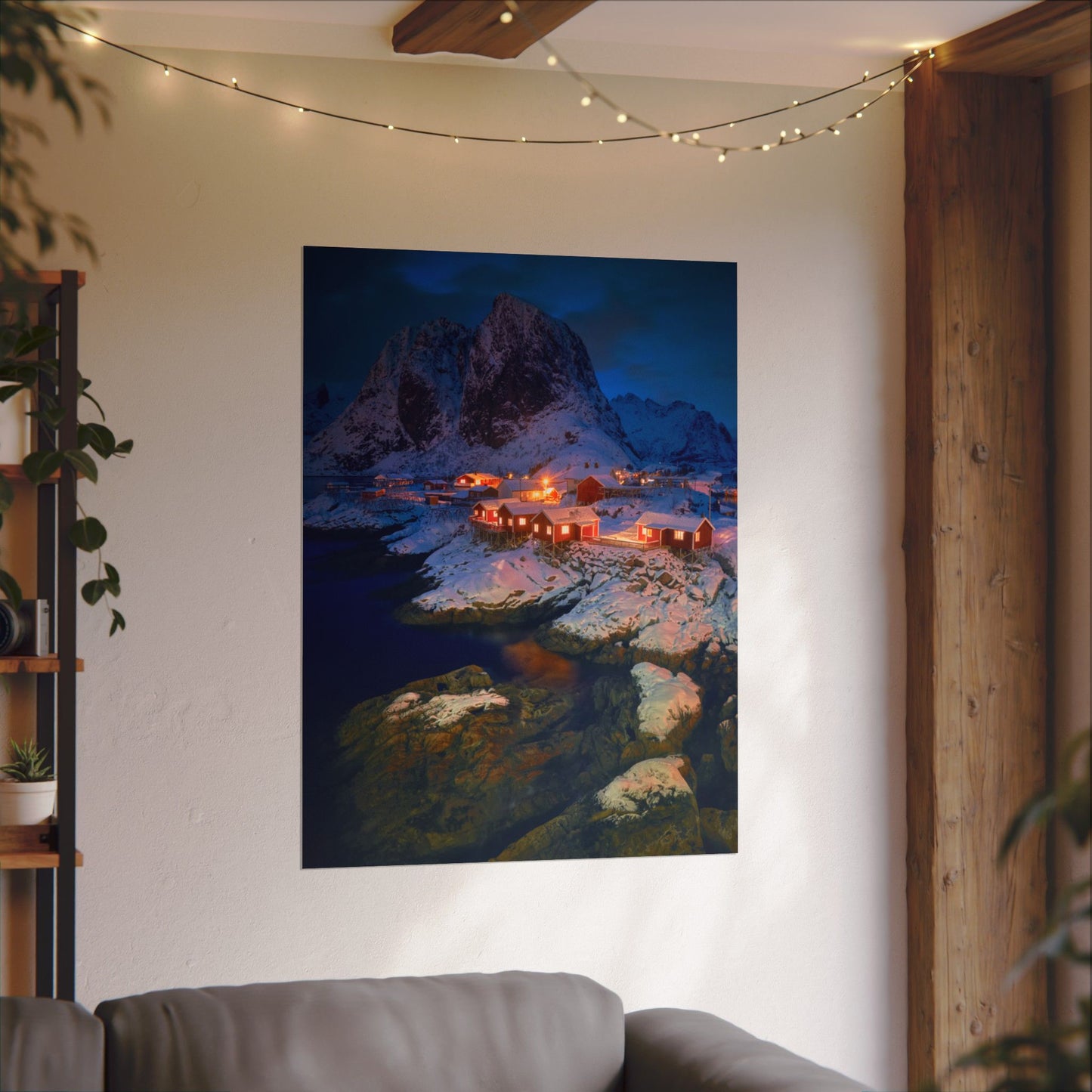 Poster of a mountainous landscape with lights on a wall above a sofa.