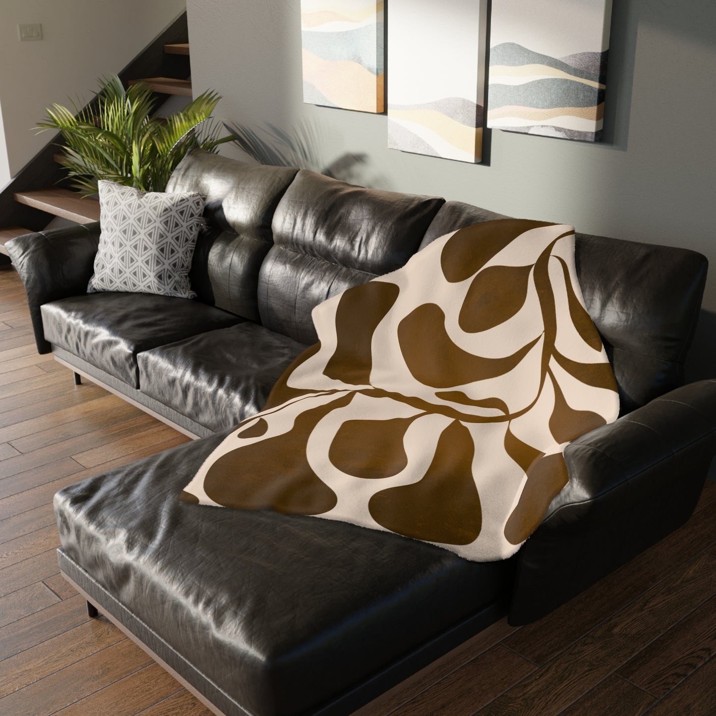 Brown and white patterned blanket draped over a dark leather sofa in a living room.
