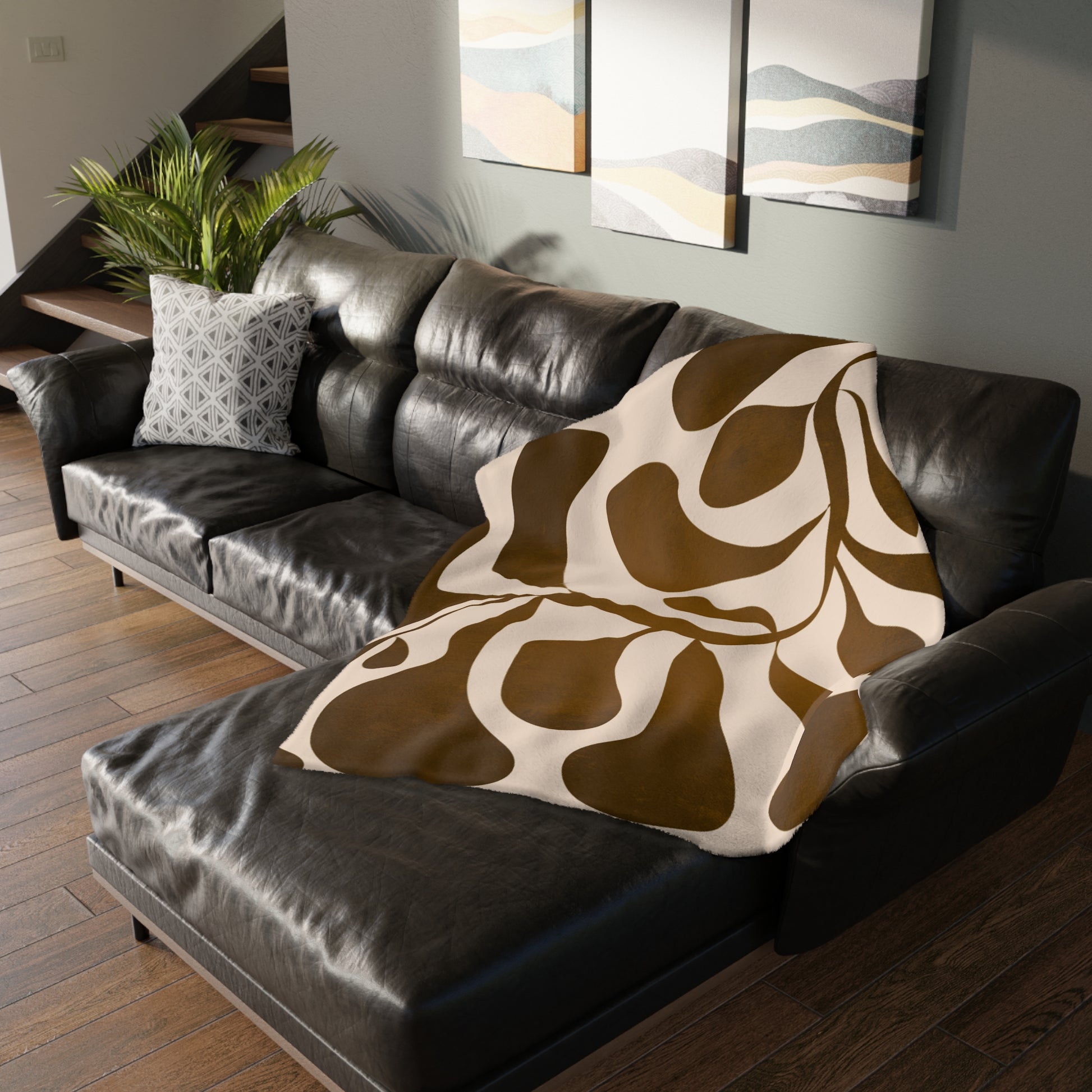 Brown and white patterned blanket draped over a dark leather sofa in a living room.
