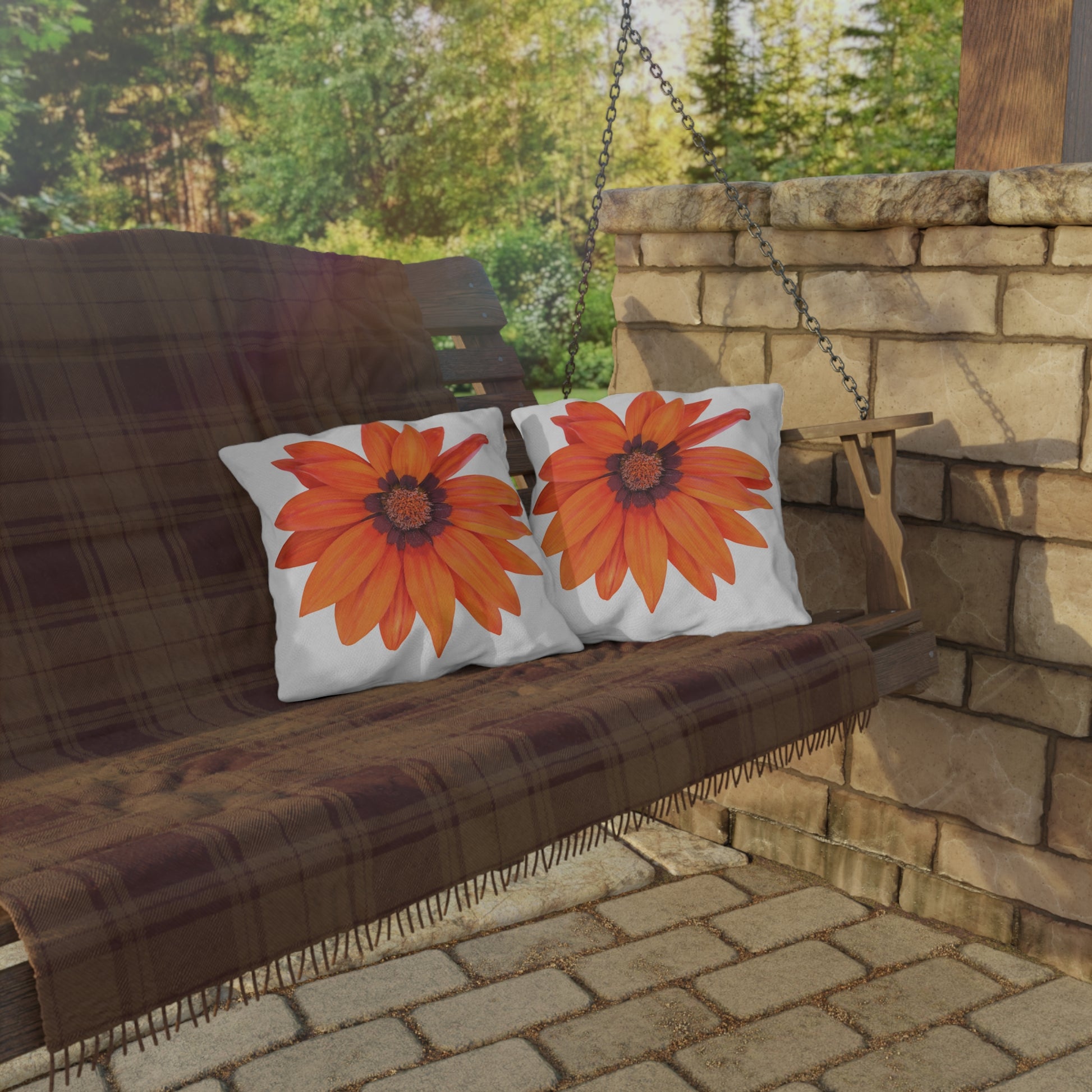 Wooden porch swing with plaid blanket and sunflower-patterned pillows in an outdoor setting.