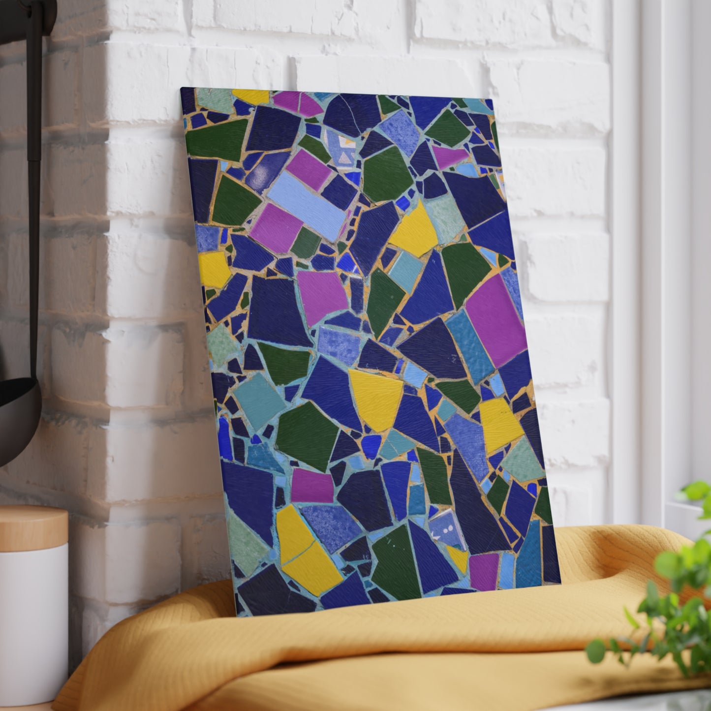 Colorful mosaic art piece leaning against a white brick wall.