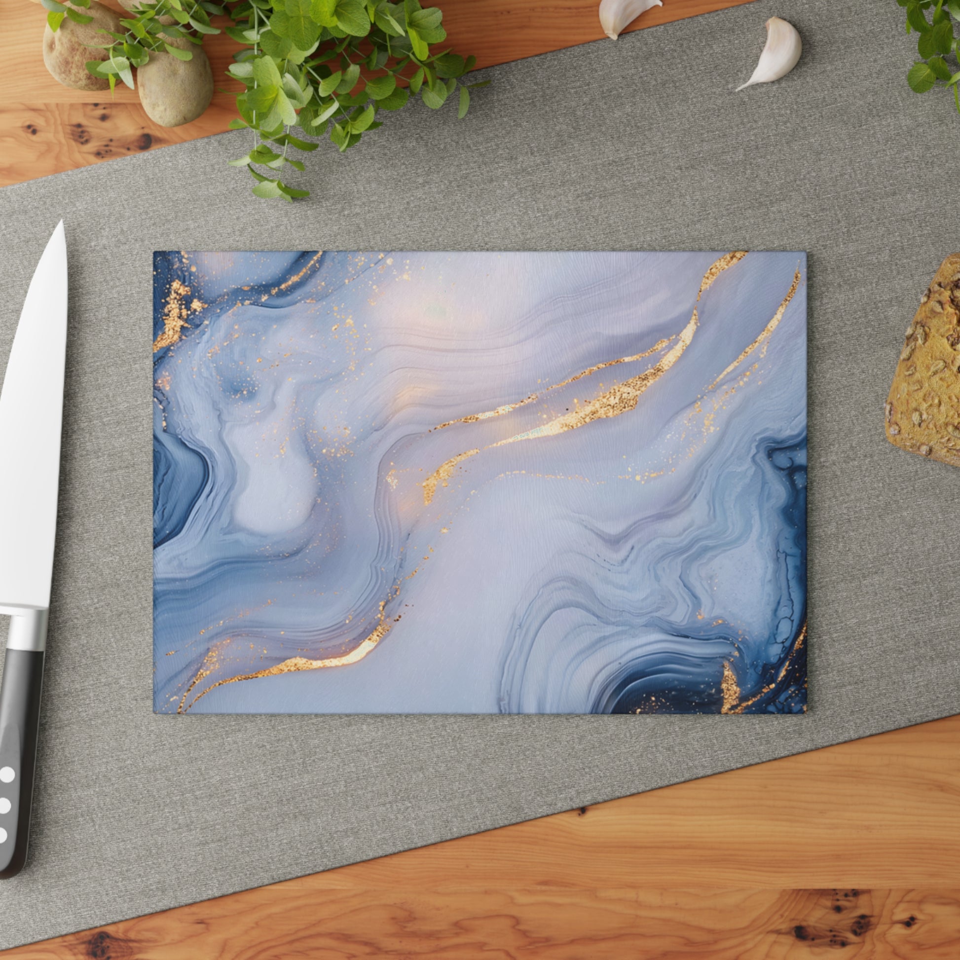 Marble-patterned cutting board with gold accents on a gray surface with a knife.