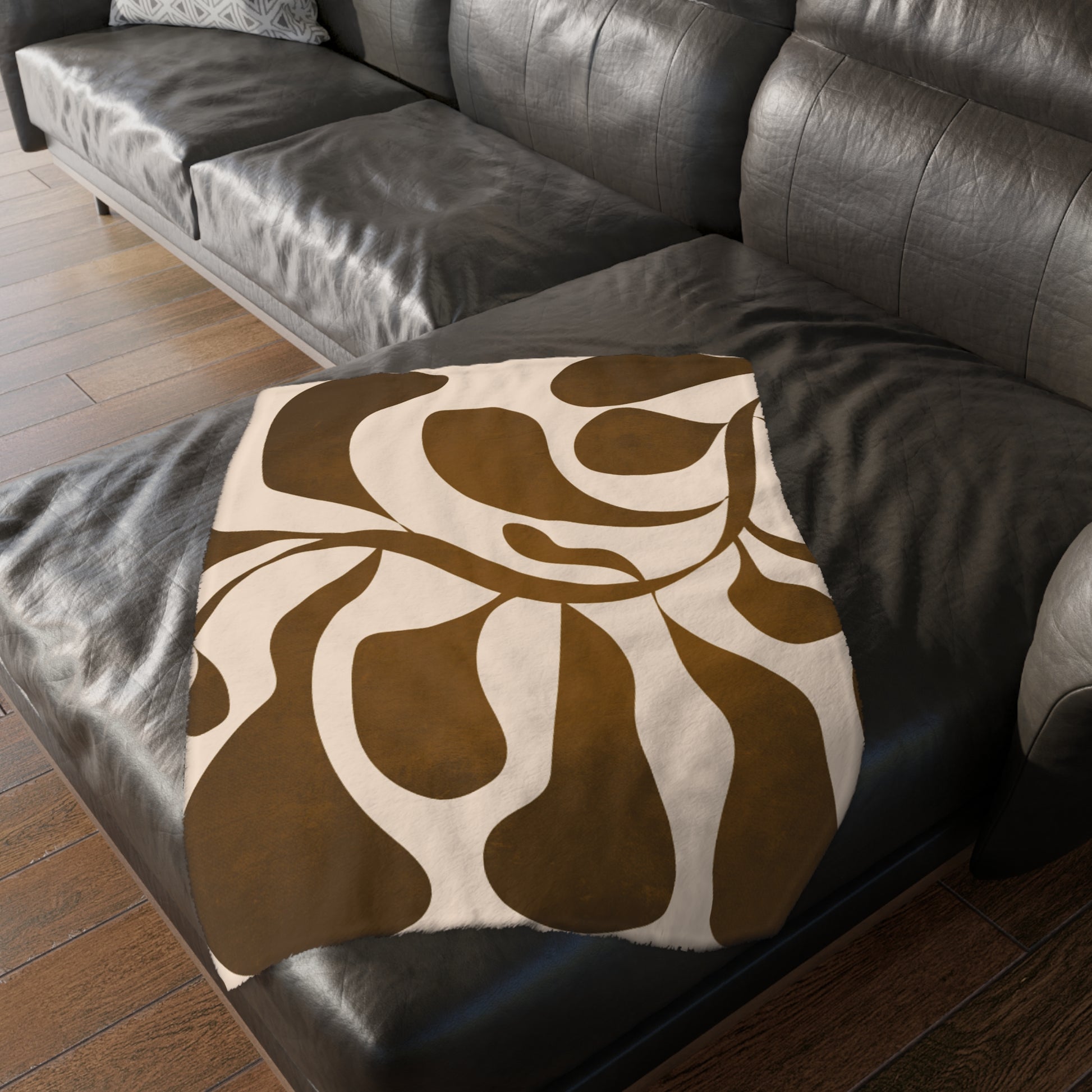 Brown and beige patterned pillow on a dark leather sofa.