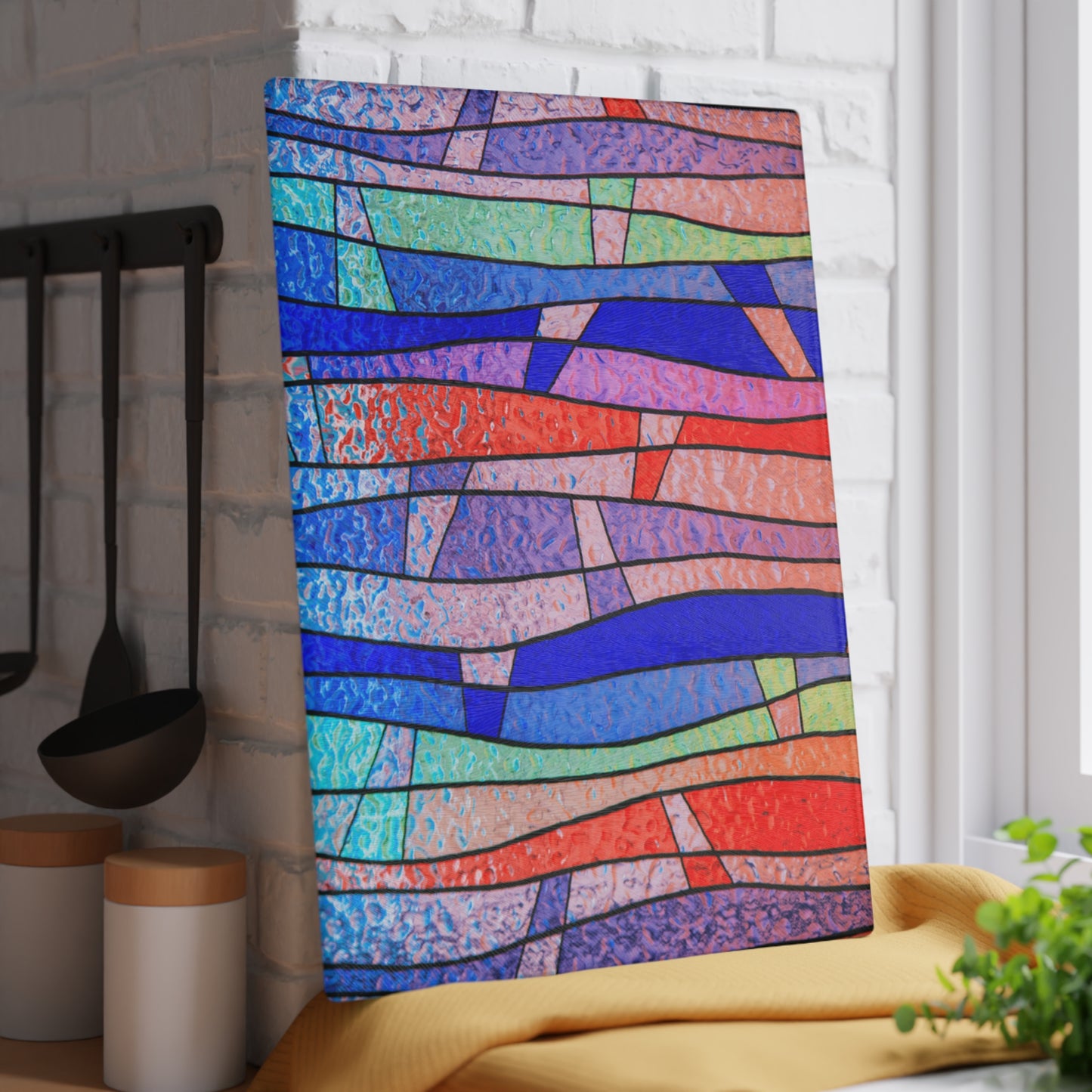 Colorful abstract patterned towel hanging on a rack in a kitchen.