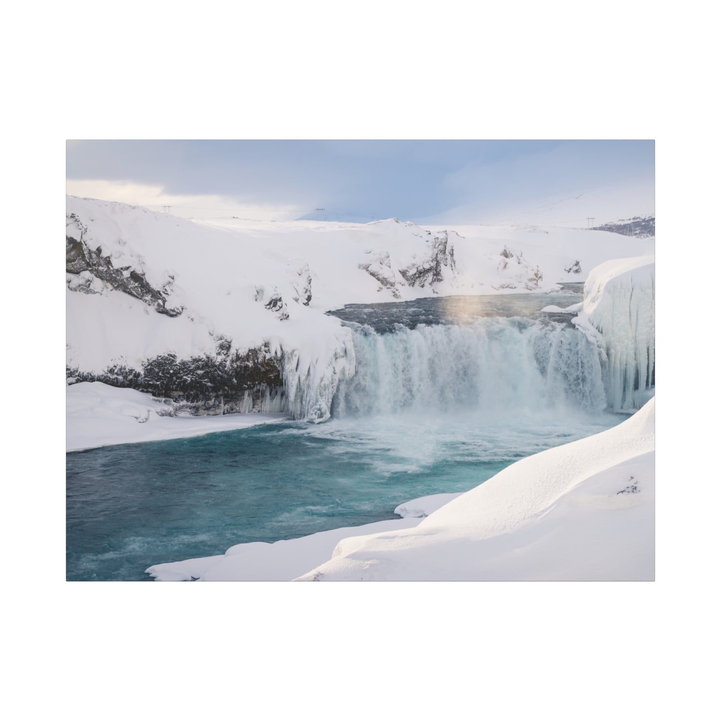 Frozen waterfall in a snowy landscape with a rainbow in the mist.
