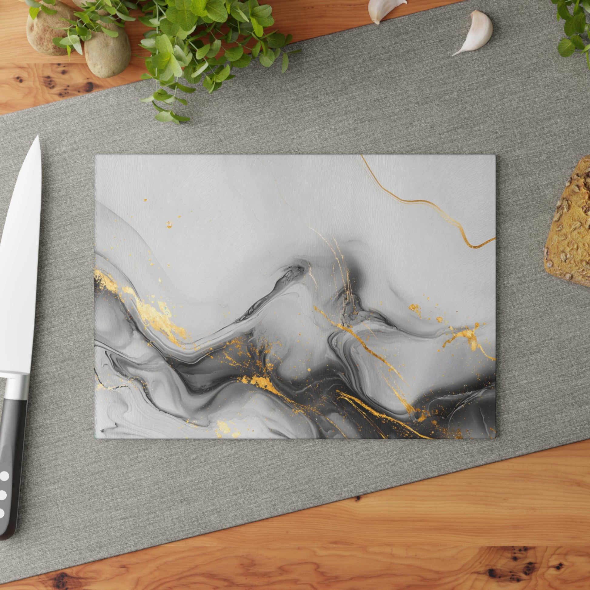 Marble-patterned cutting board with gold accents on a gray surface, surrounded by kitchen items.