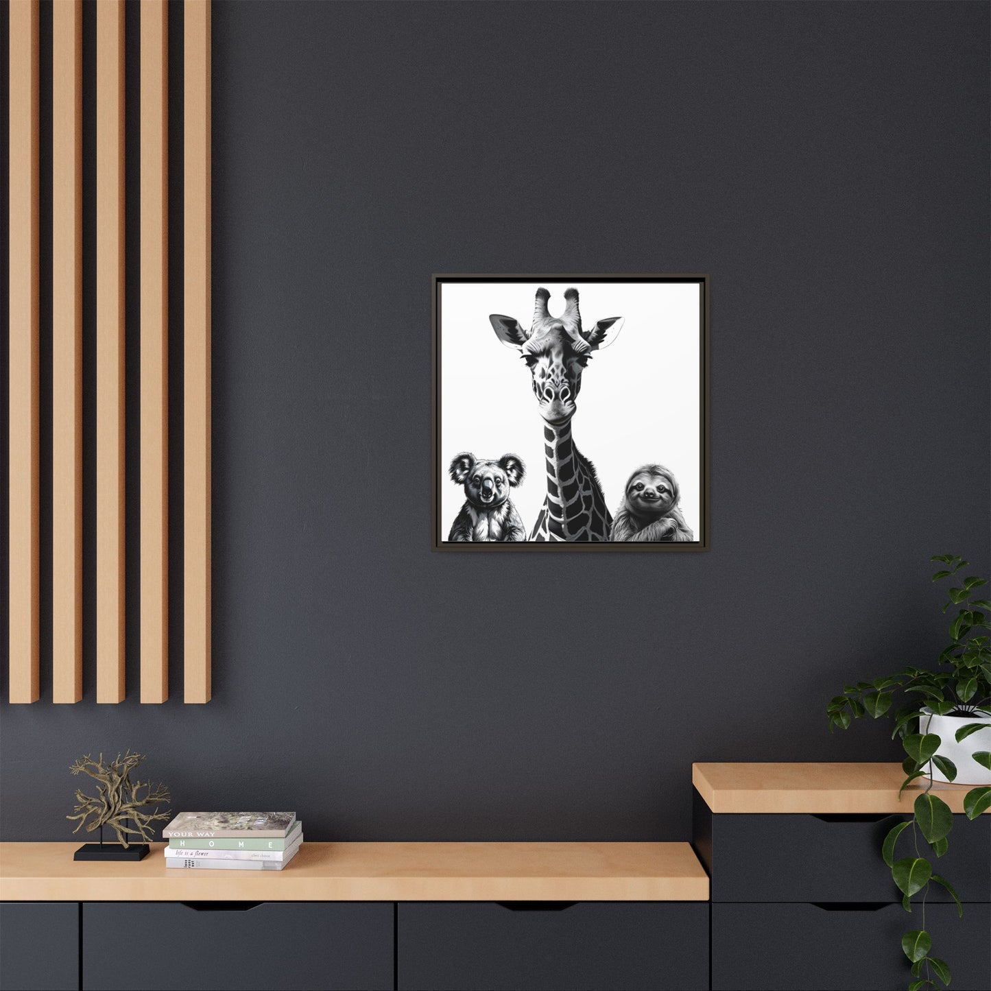 Framed artwork of a giraffe with two sloths on a dark wall above a wooden shelf.