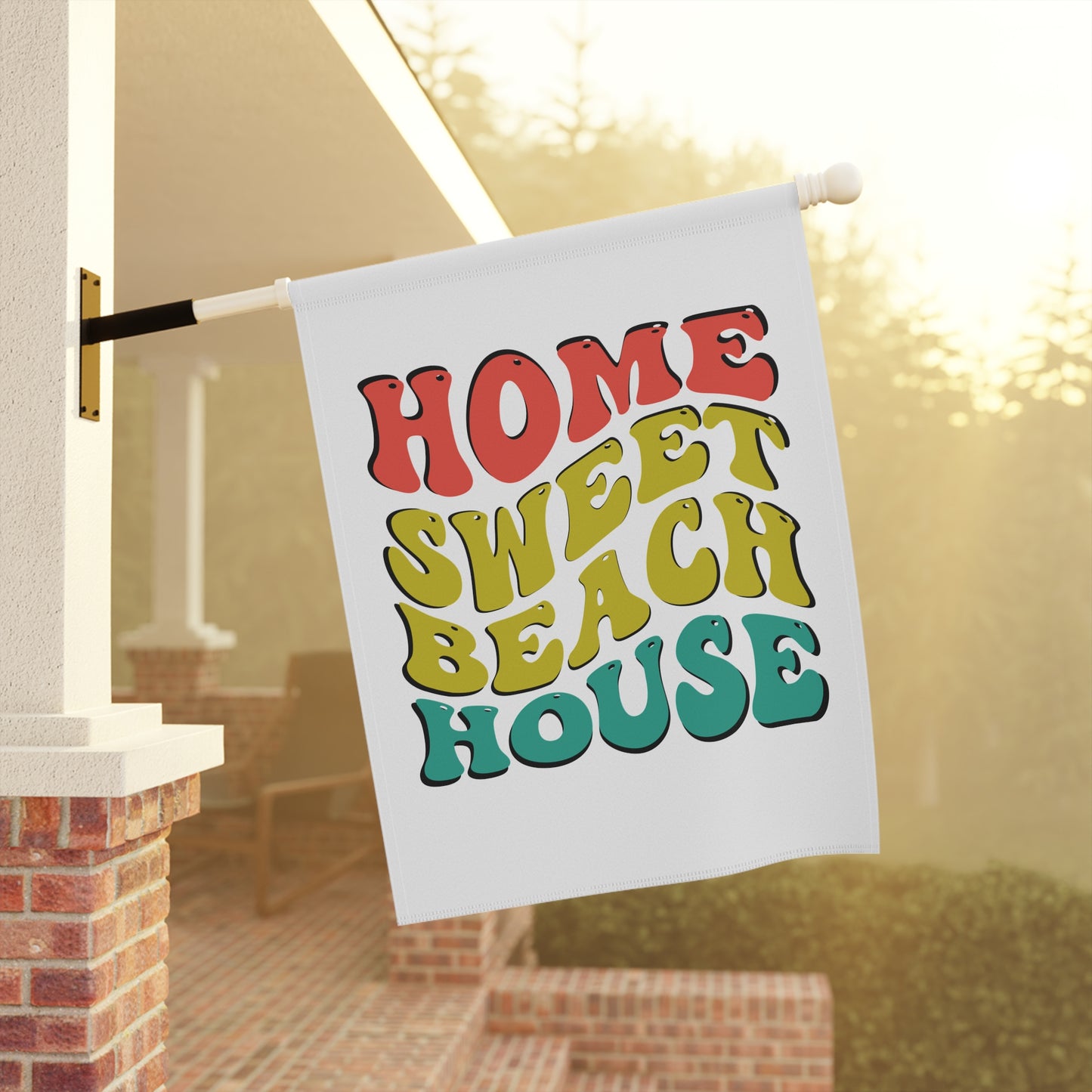 Decorative flag with 'Home Sweet Beach House' text hanging outside a house.